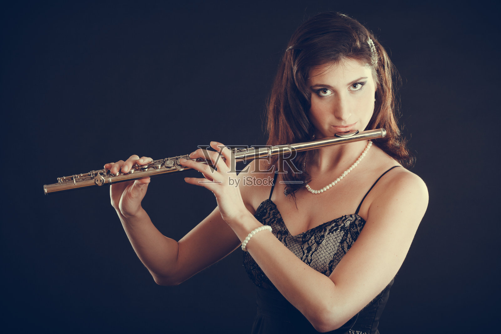 在黑色乐器上弹奏横笛的女人。照片摄影图片