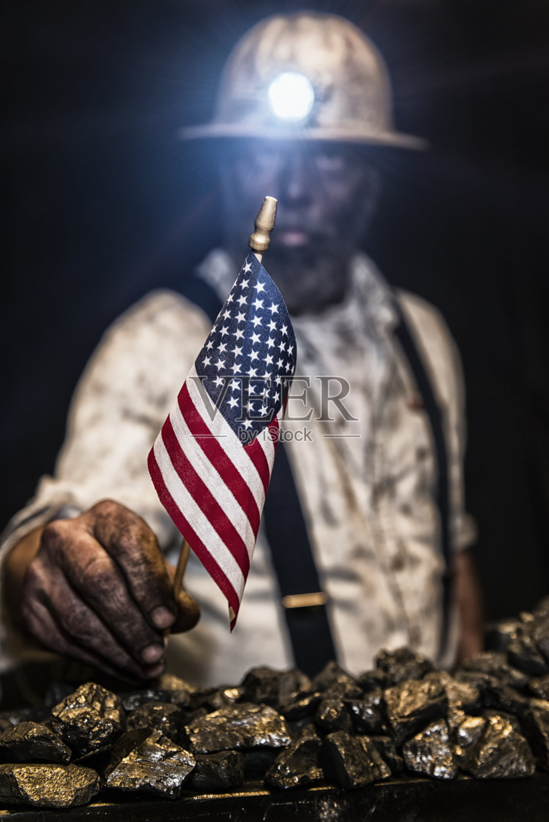 满身煤尘的矿工举着一面小美国国旗看着镜头照片摄影图片