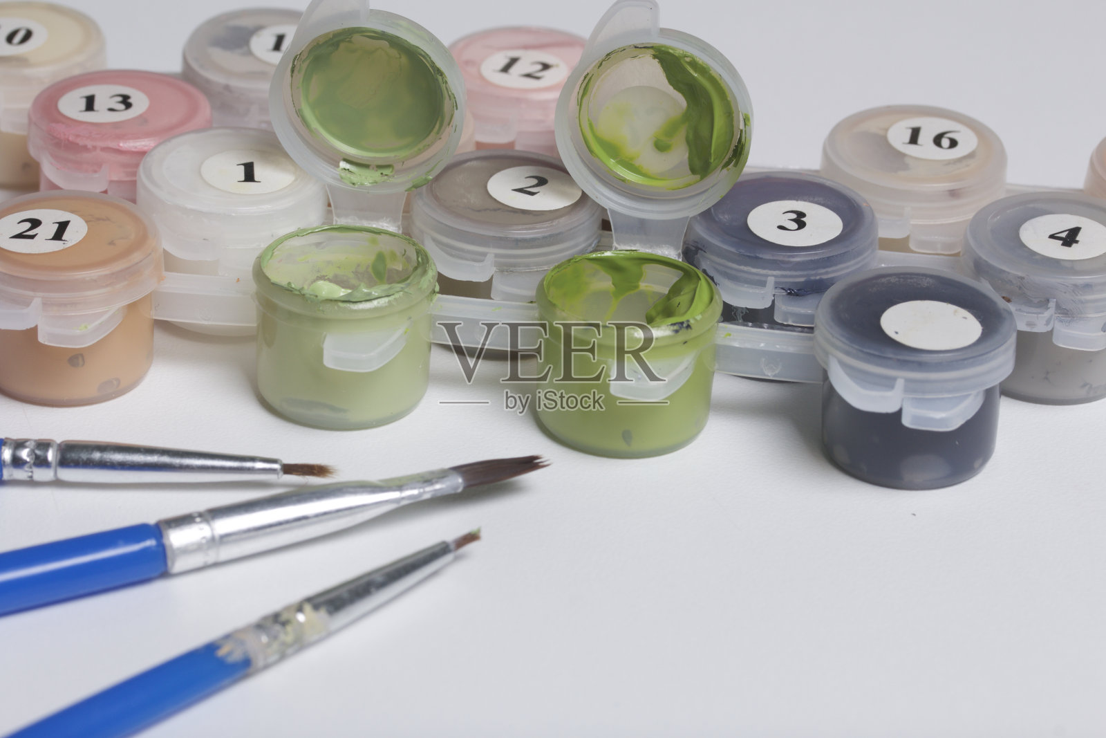 用数字绘制的颜料。几个装有油漆的容器被打开了。附近有流苏。照片摄影图片