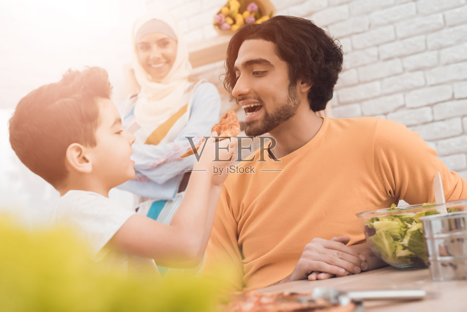 一个小男孩和他的阿拉伯父亲一起吃披萨。照片摄影图片