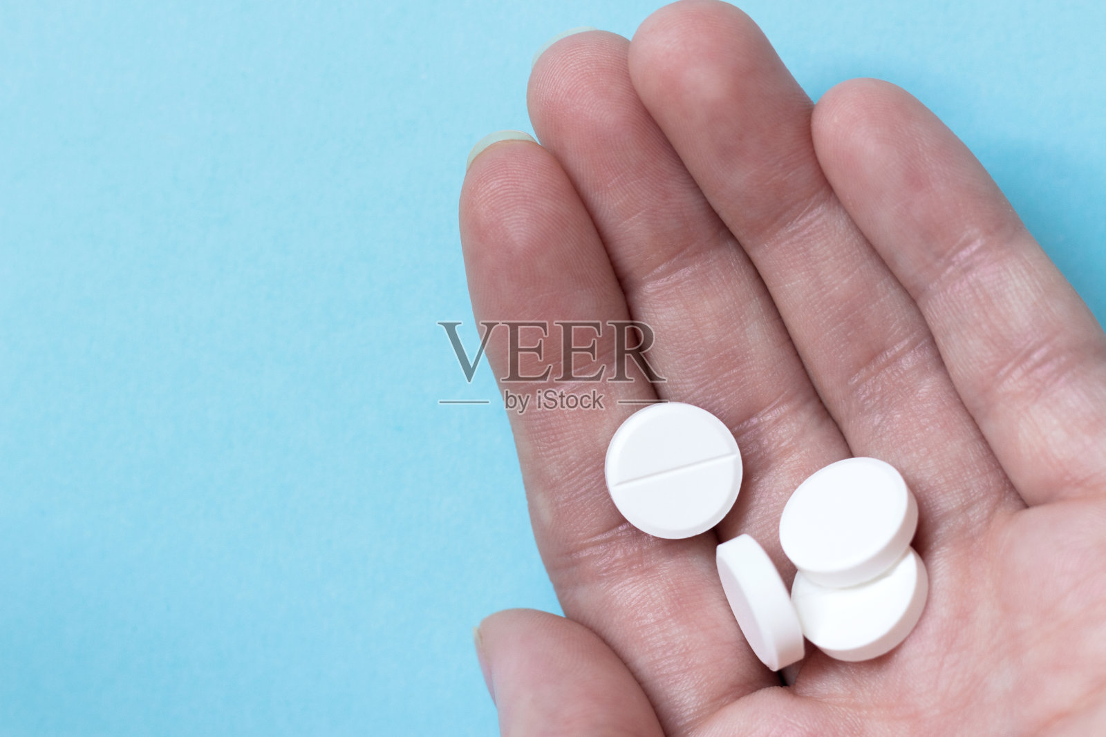 女性手搓圆丸。蓝色背景。的药物。医学概念照片摄影图片