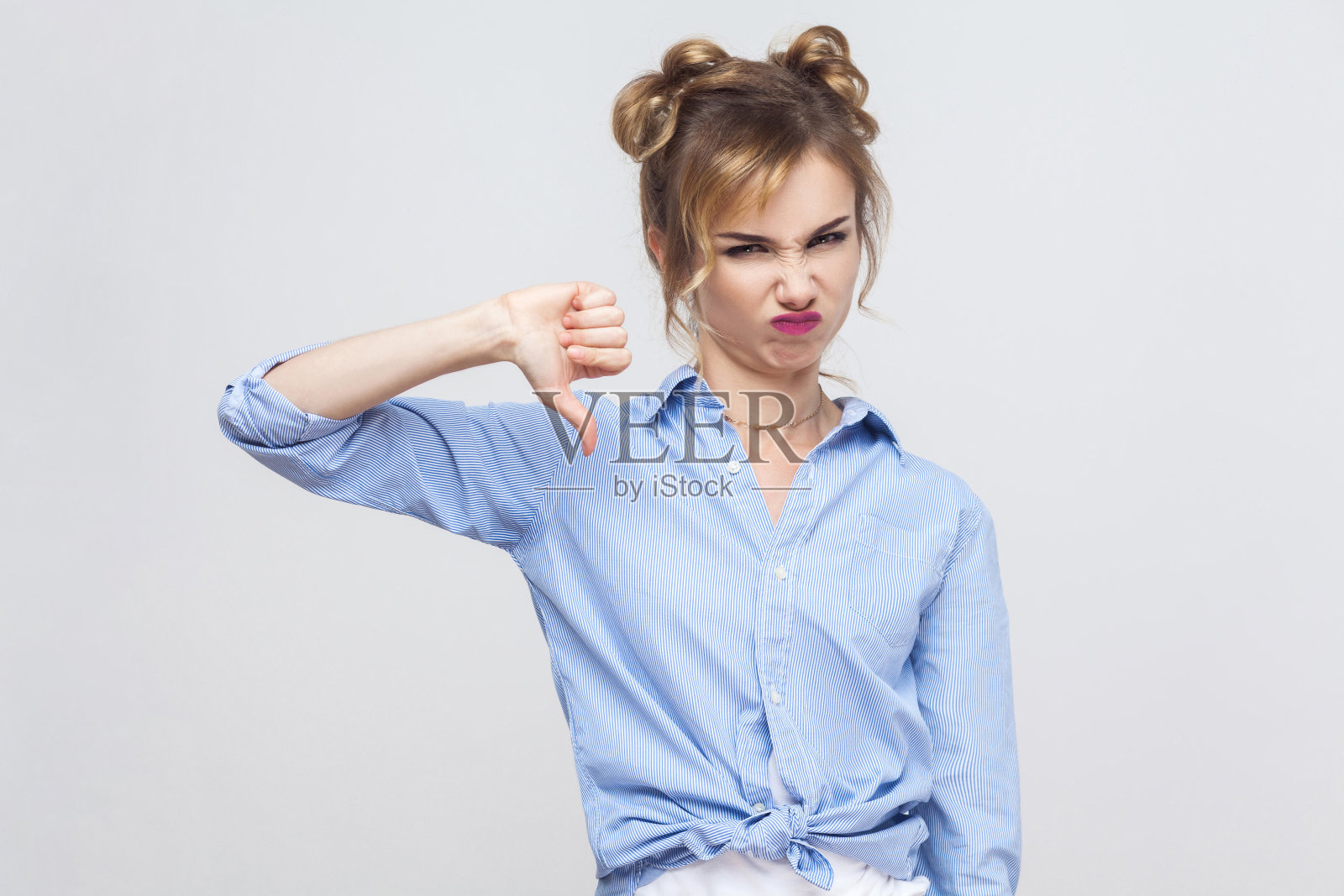 年轻的成年女子拇指向下，孤立在灰色背景上。照片摄影图片