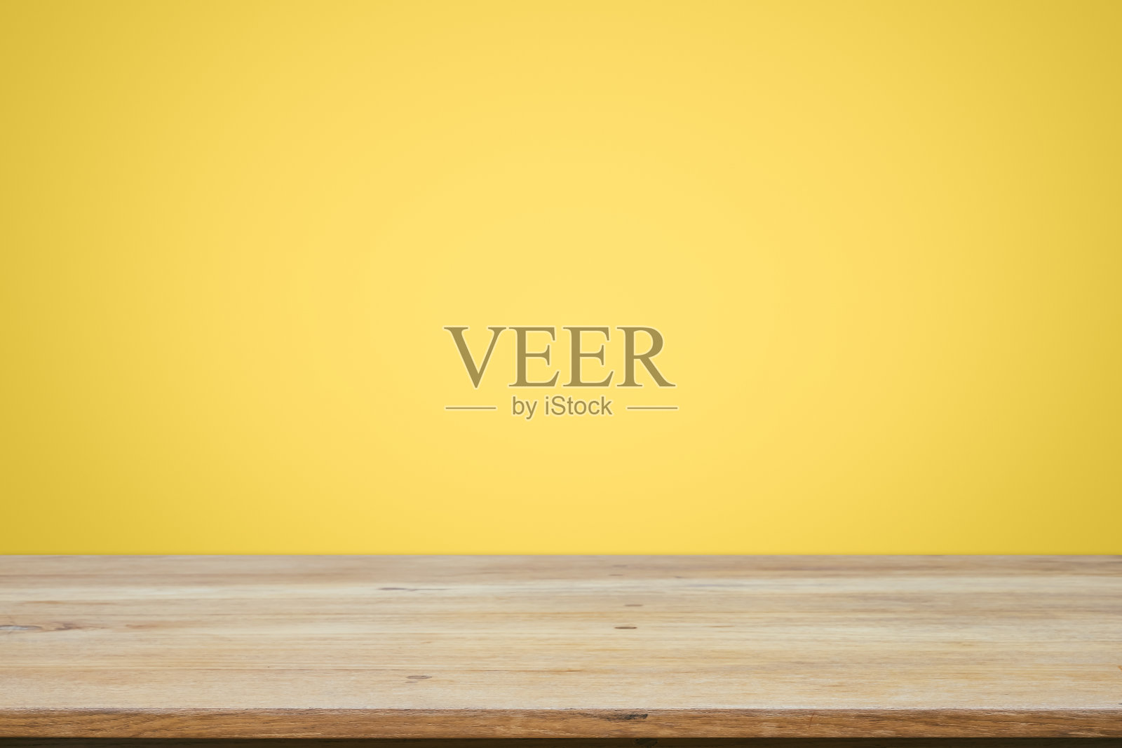 在黄色墙纸背景上的空木制甲板桌子。照片摄影图片