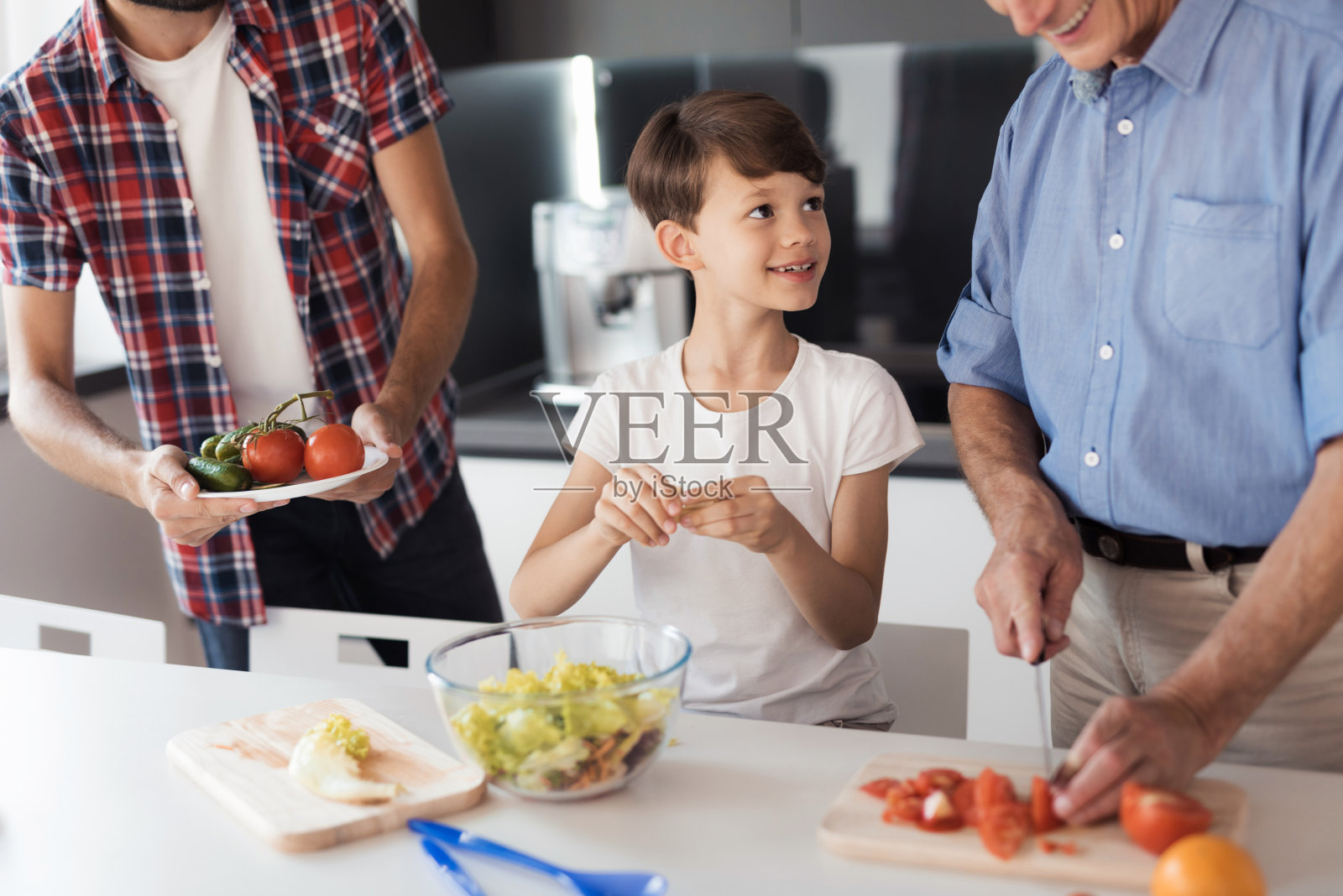 一个男孩和他的父亲和祖父在为感恩节准备沙拉照片摄影图片