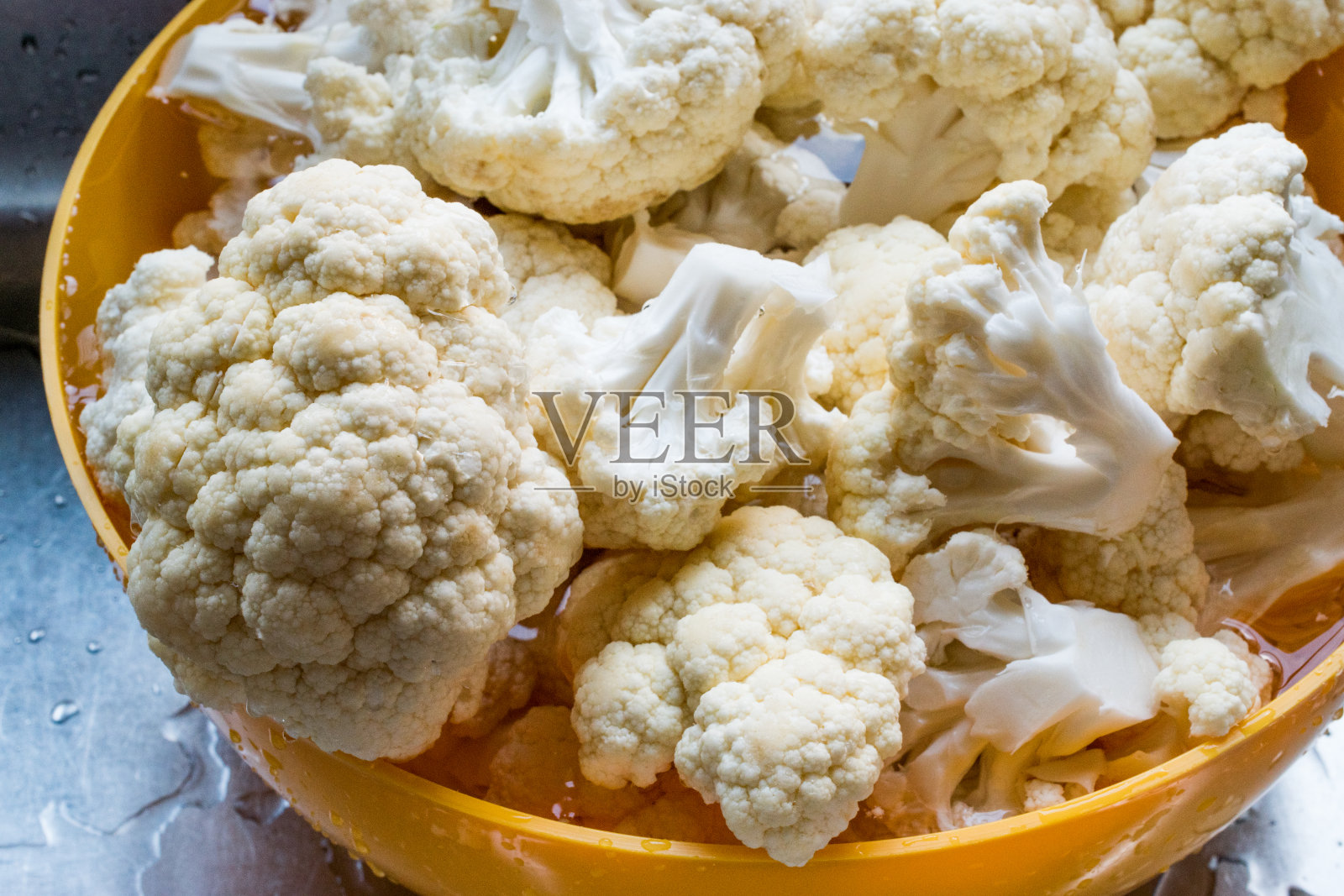 洗净的花椰菜放在黄色碗里。照片摄影图片