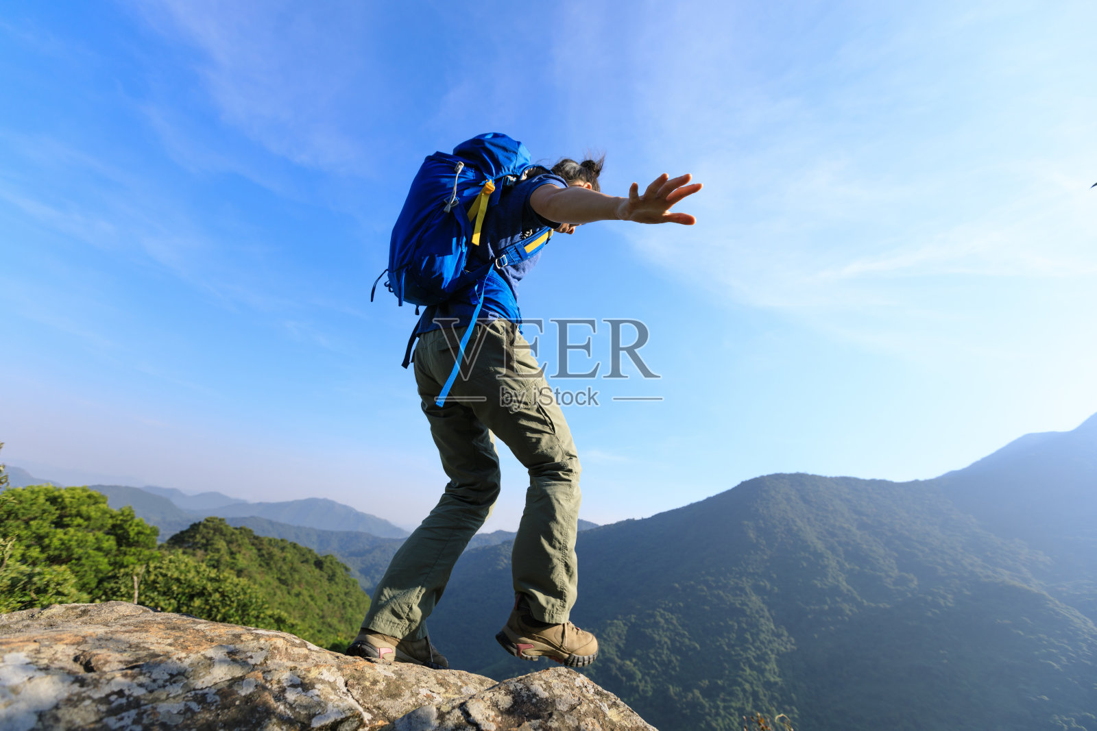 勇敢的女性徒步旅行者走到山顶的悬崖边缘照片摄影图片