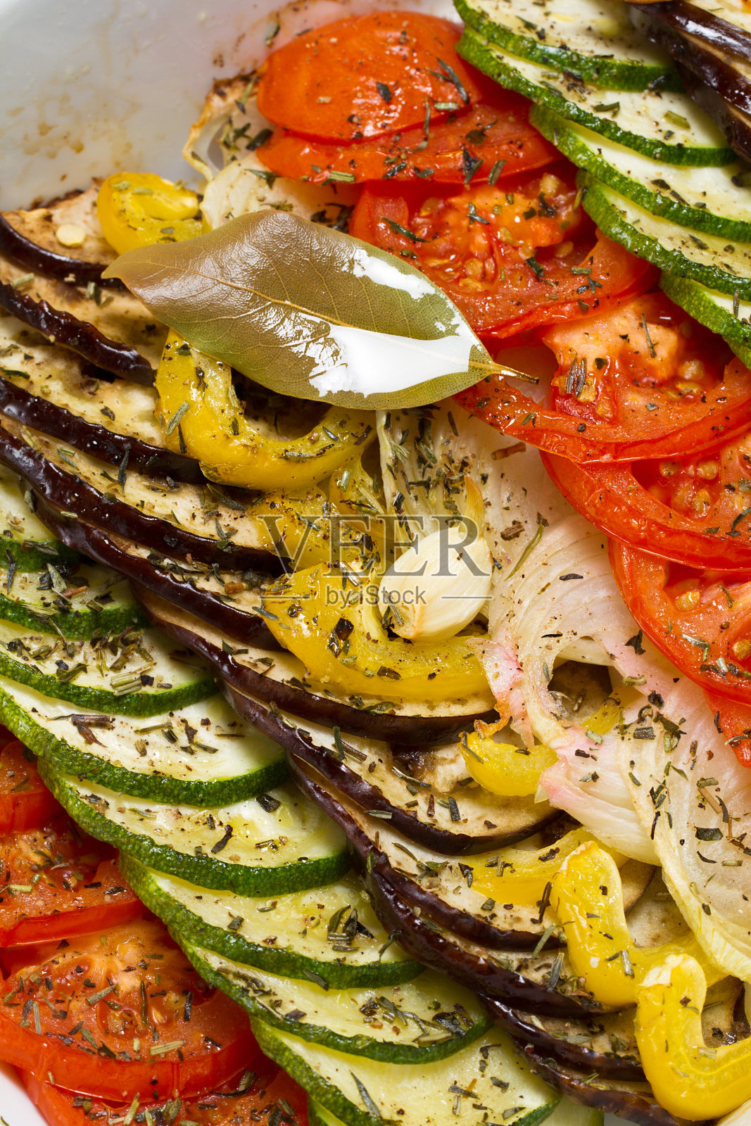 切片蔬菜与香草、橄榄油和月桂叶一起烘烤照片摄影图片