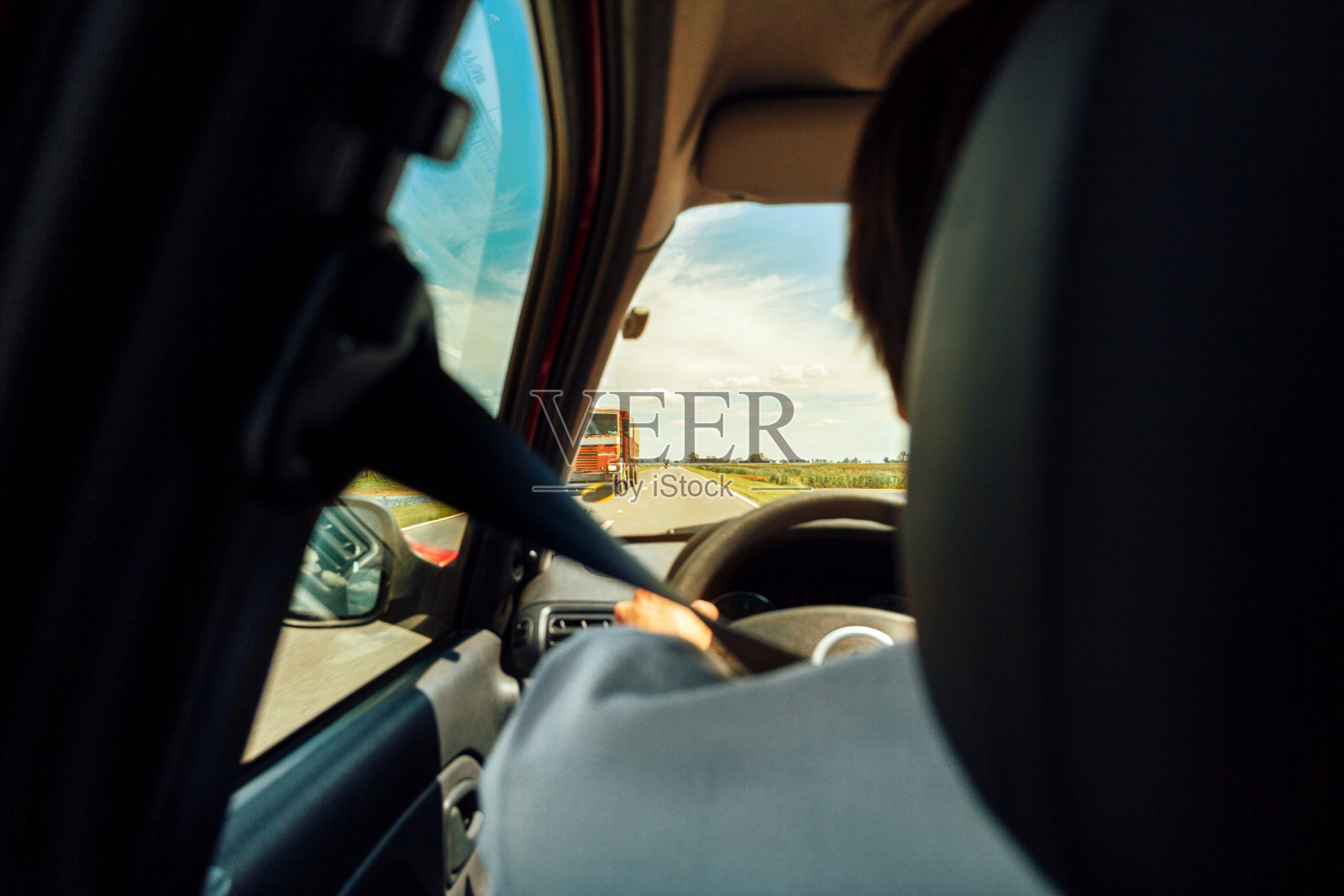 从后面看到的一个人开着一辆汽车在路上，前面有一辆卡车照片摄影图片