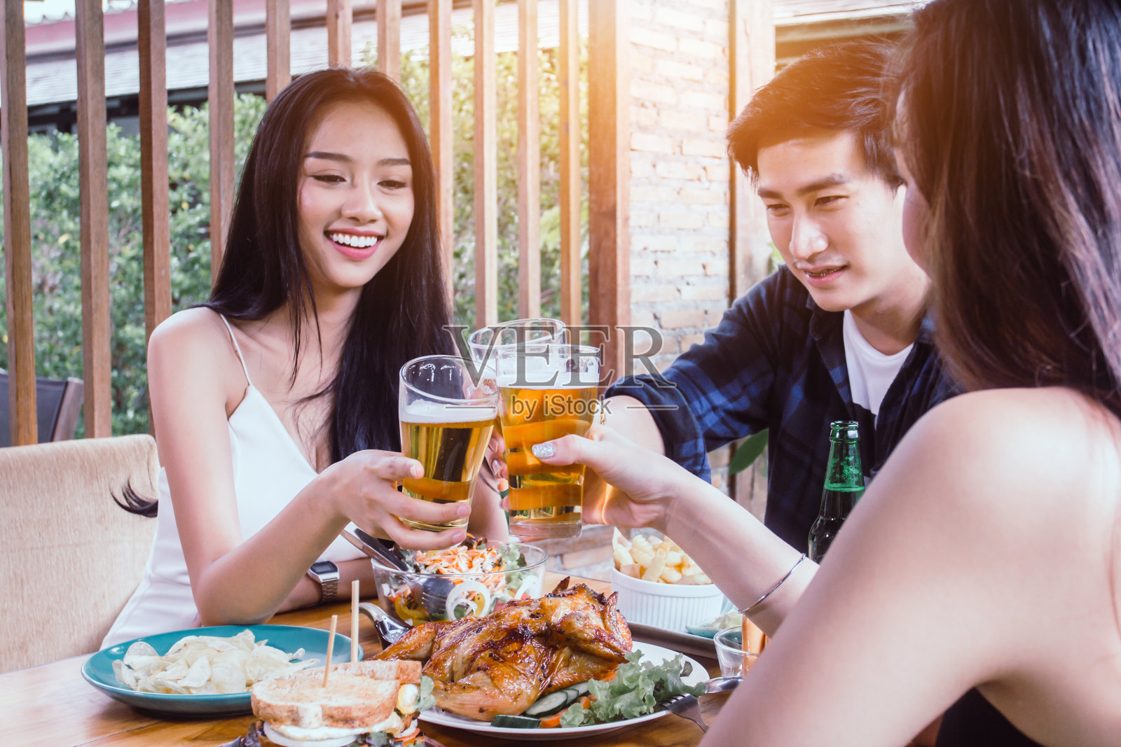 两名亚洲女子和一名男子。喝啤酒，微笑。庆祝派对，快乐饮食概念照片摄影图片