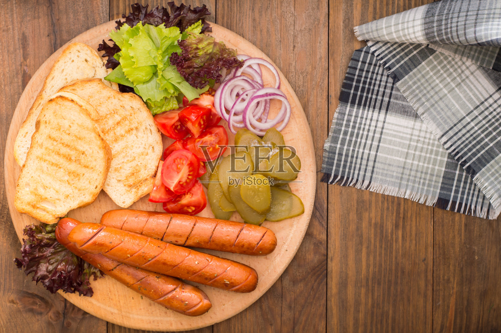 食物集热狗，香肠，黄瓜罐头，生菜叶，西红柿，洋葱，面包丁在木制的背景。特写镜头。俯视图照片摄影图片