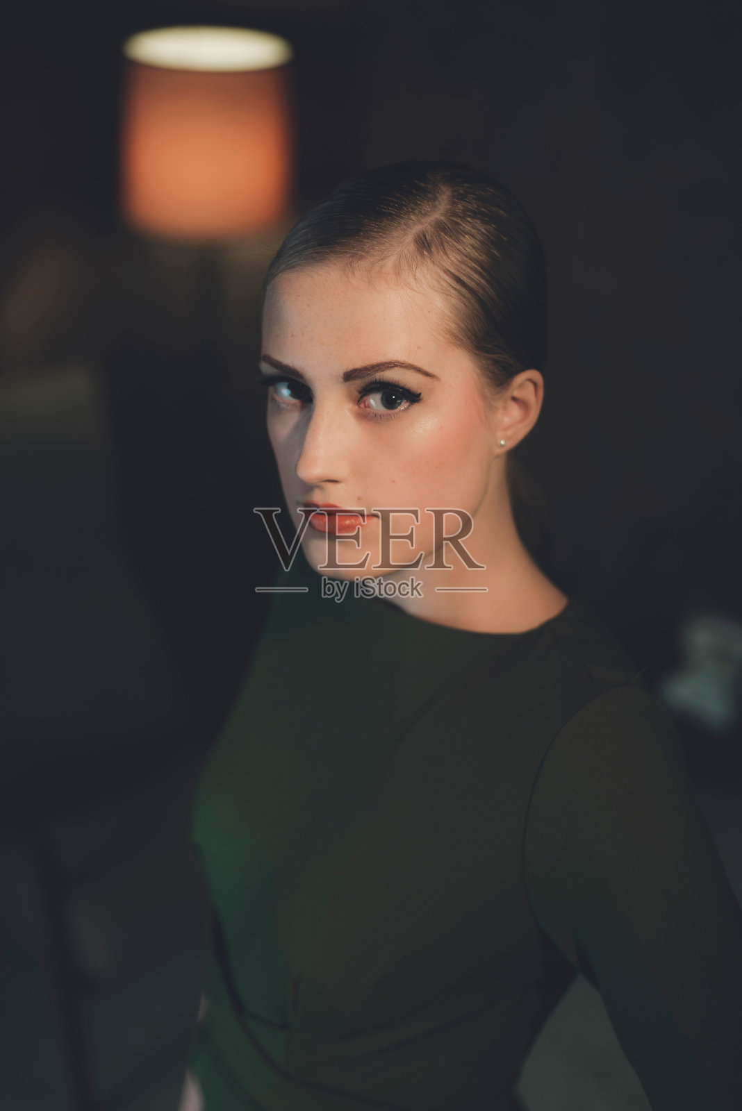 穿着绿色裙子的复古女人晚上站在房间里。照片摄影图片