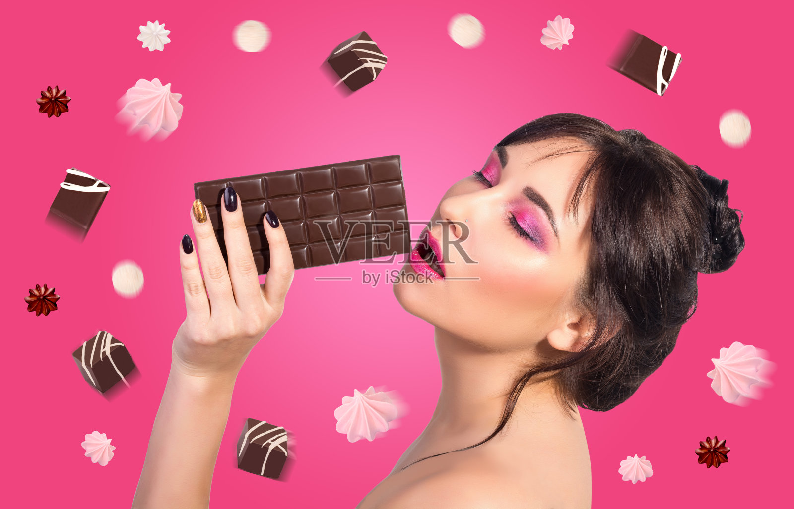 女人和巧克力。美丽的年轻女子正在吃粉红色背景上的巧克力。照片摄影图片