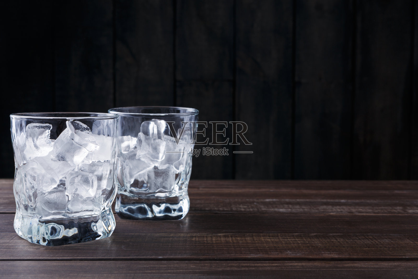 深色背景上有冰块的玻璃杯照片摄影图片