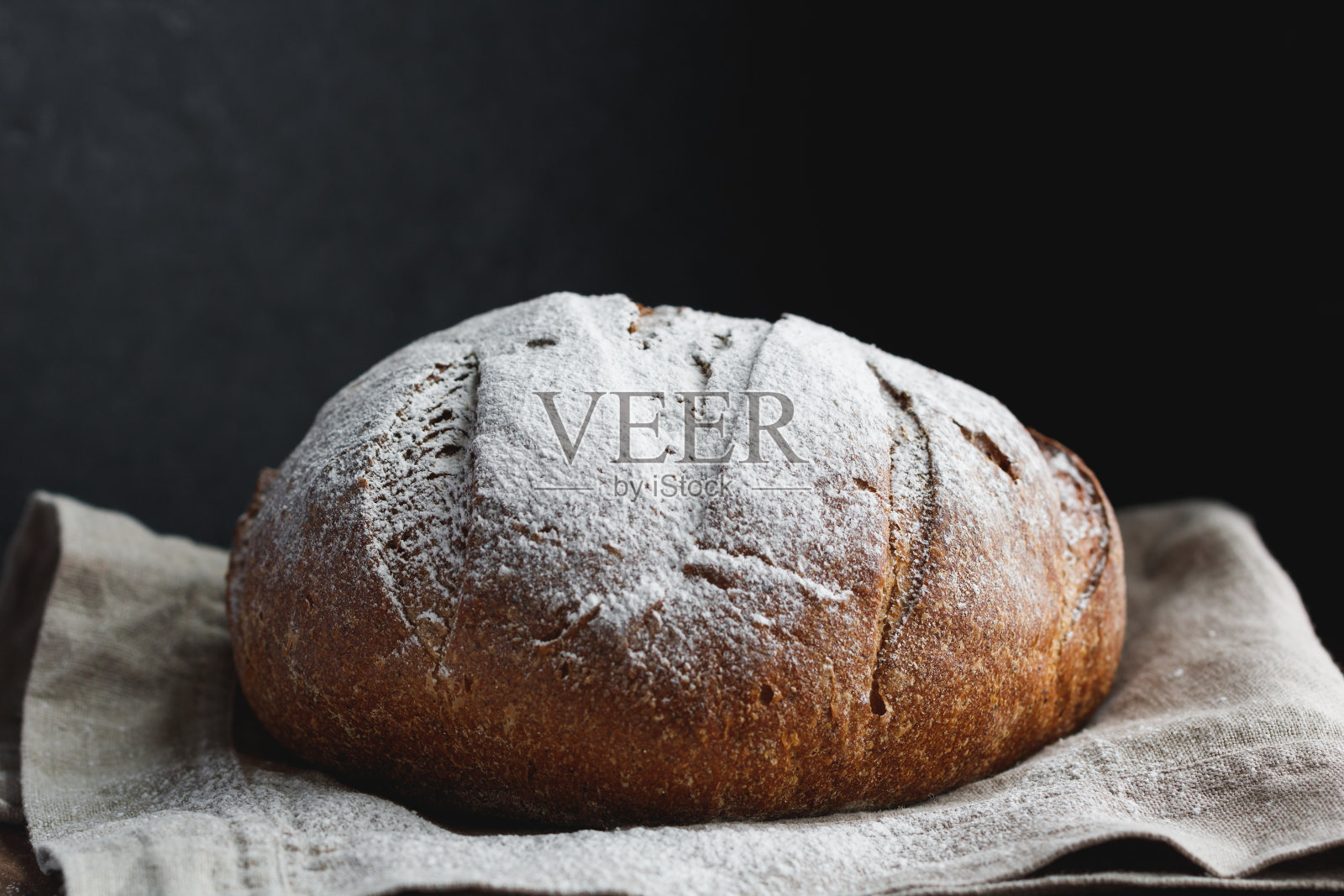 特写新鲜黑麦面包在一个黑色的背景。照片摄影图片