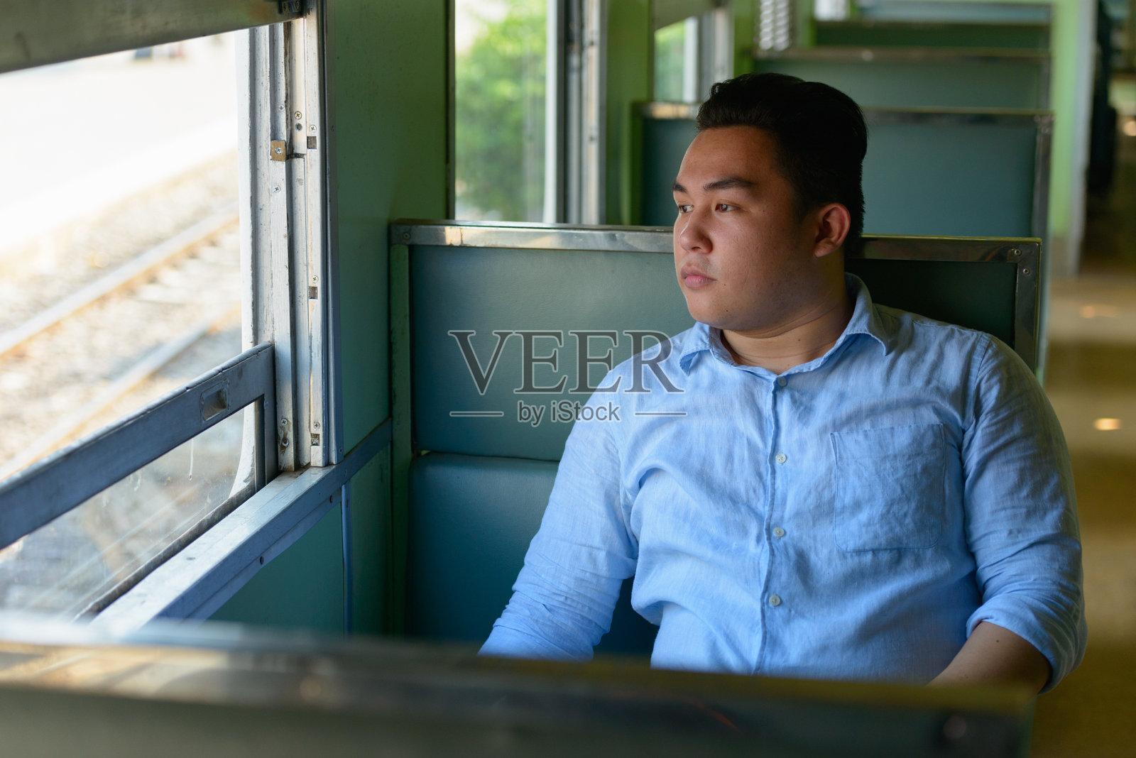 年轻英俊的亚洲游客坐在火车站的火车上照片摄影图片