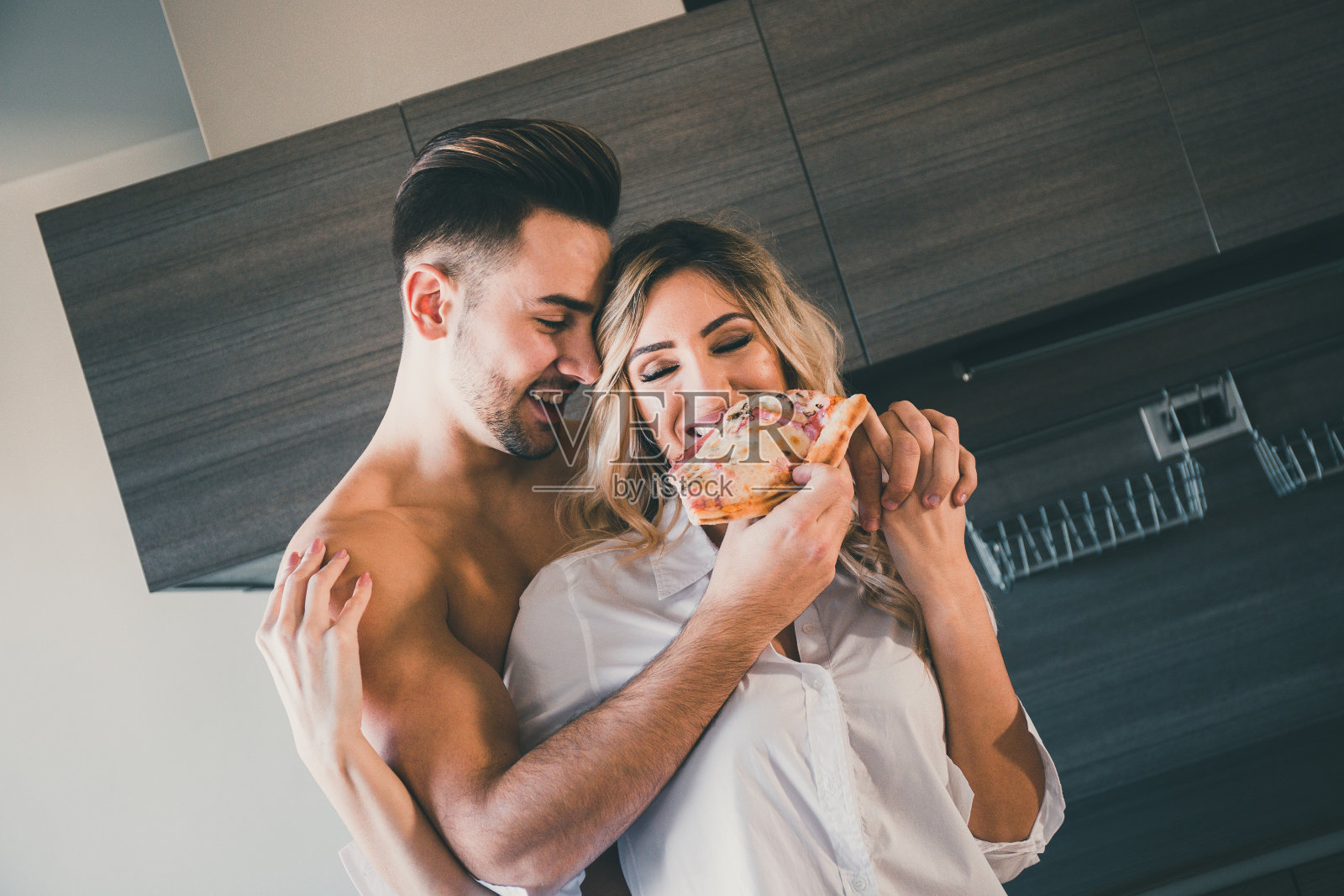 男友从后面拥抱女友，同时分享一块披萨照片摄影图片
