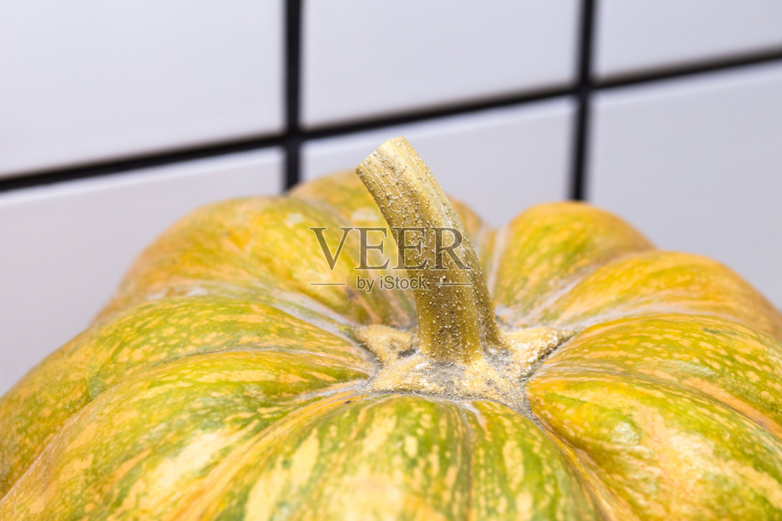 在白色瓷砖的背景下，黄色南瓜顶部有干脊照片摄影图片