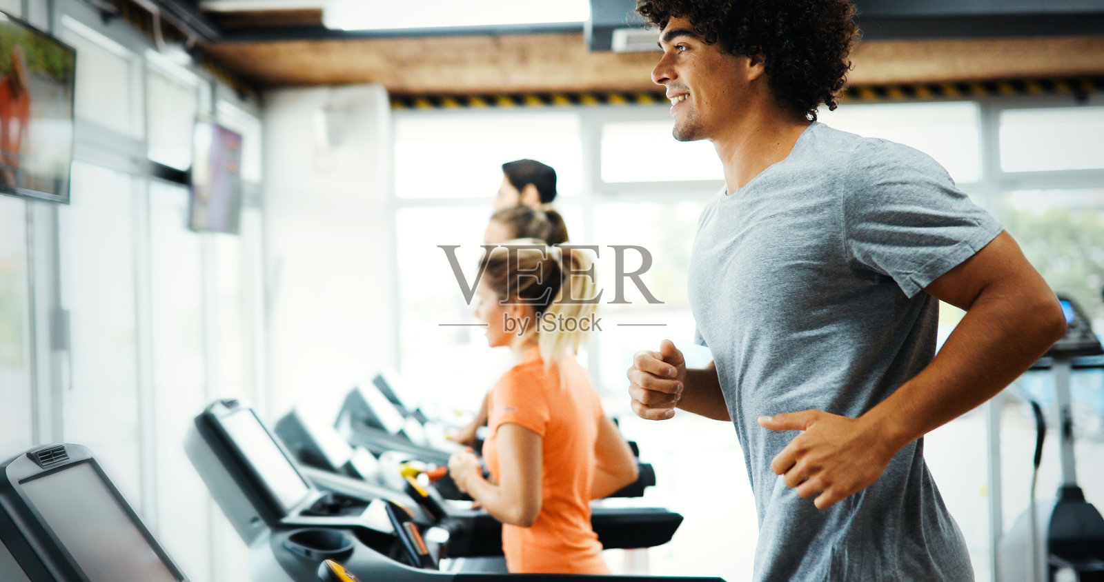 年轻帅气的男人在健身房做有氧运动照片摄影图片