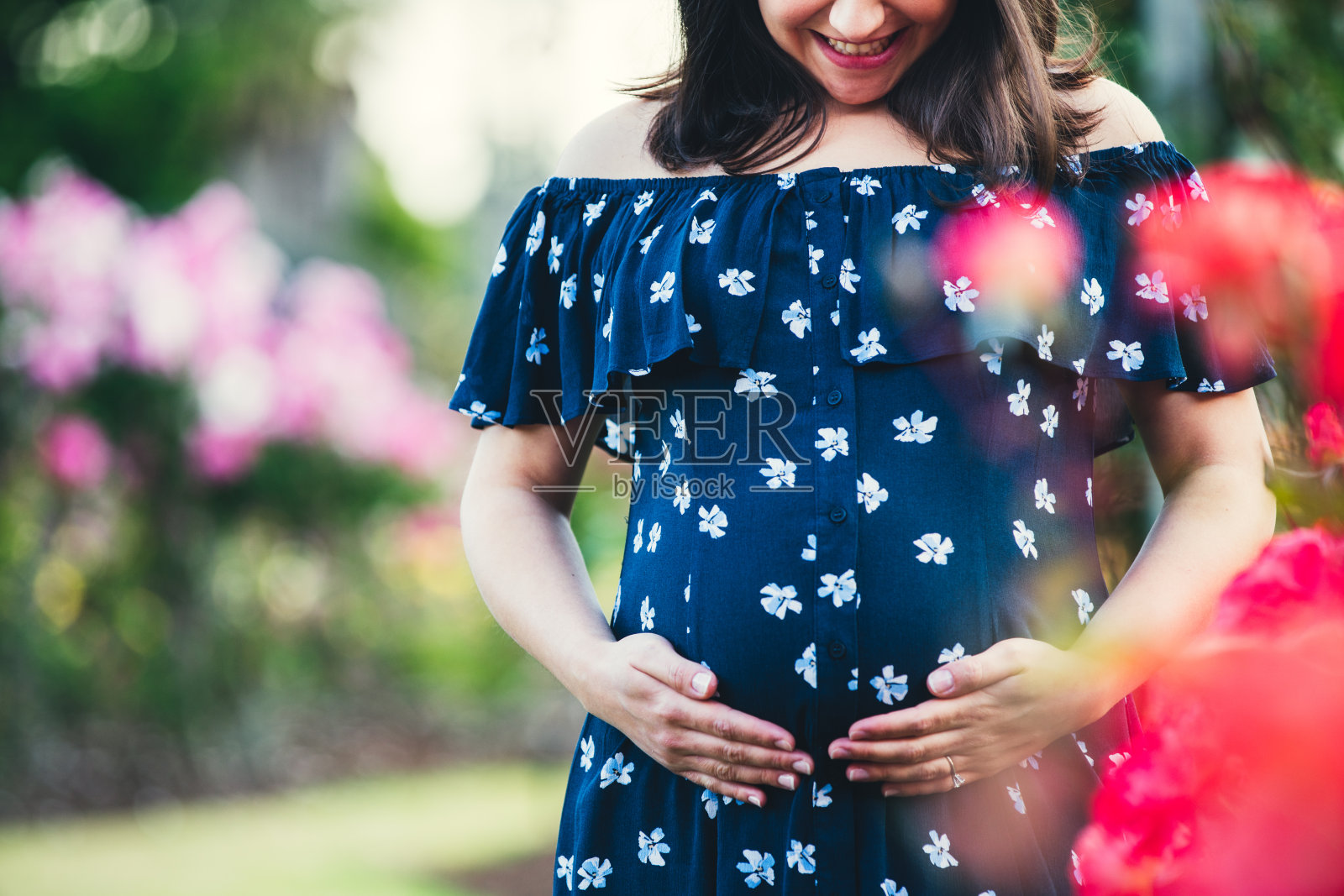 孕妇把手放在肚子下面。照片摄影图片
