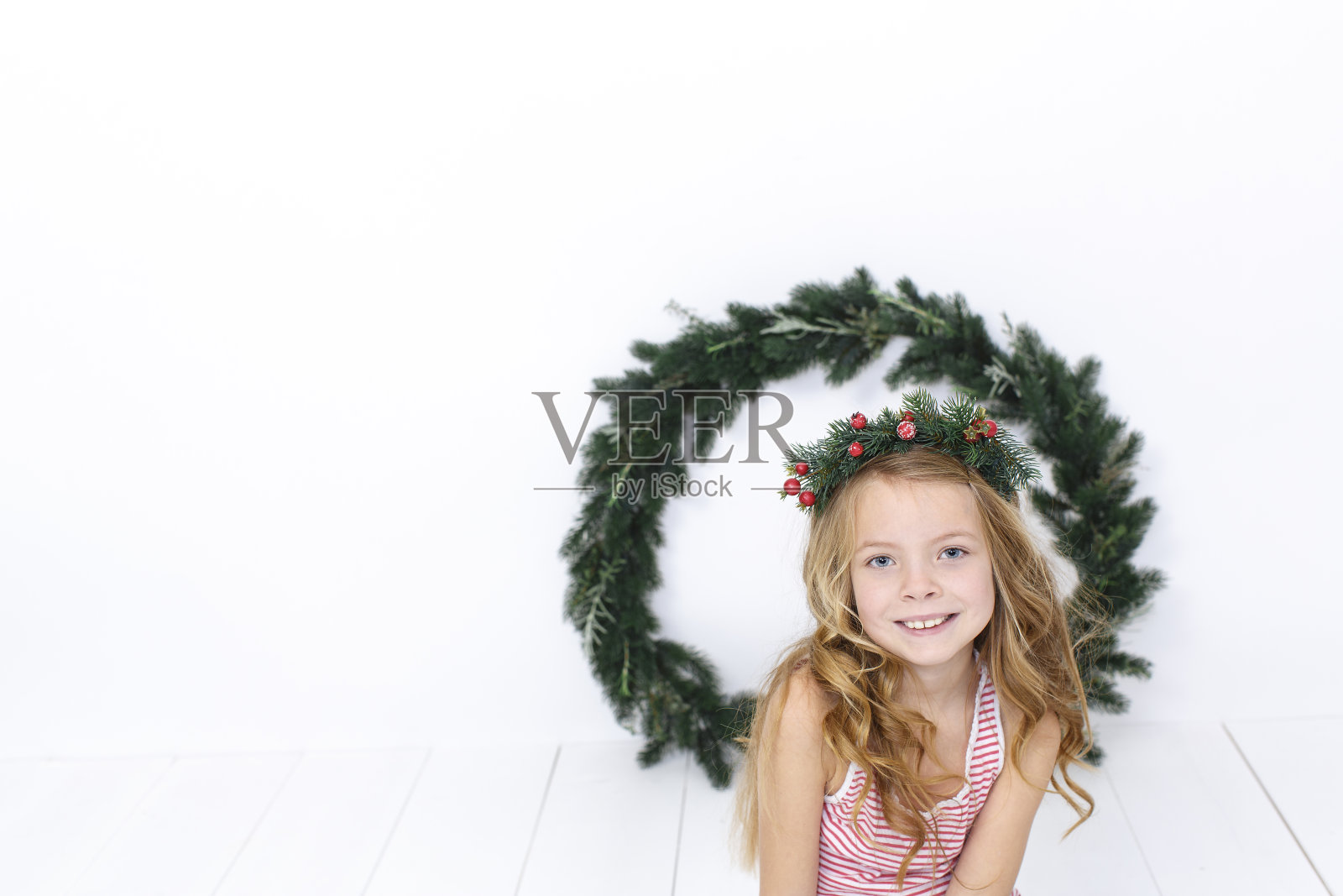 白色地板上挂着圣诞花环的快乐美丽的女孩照片摄影图片