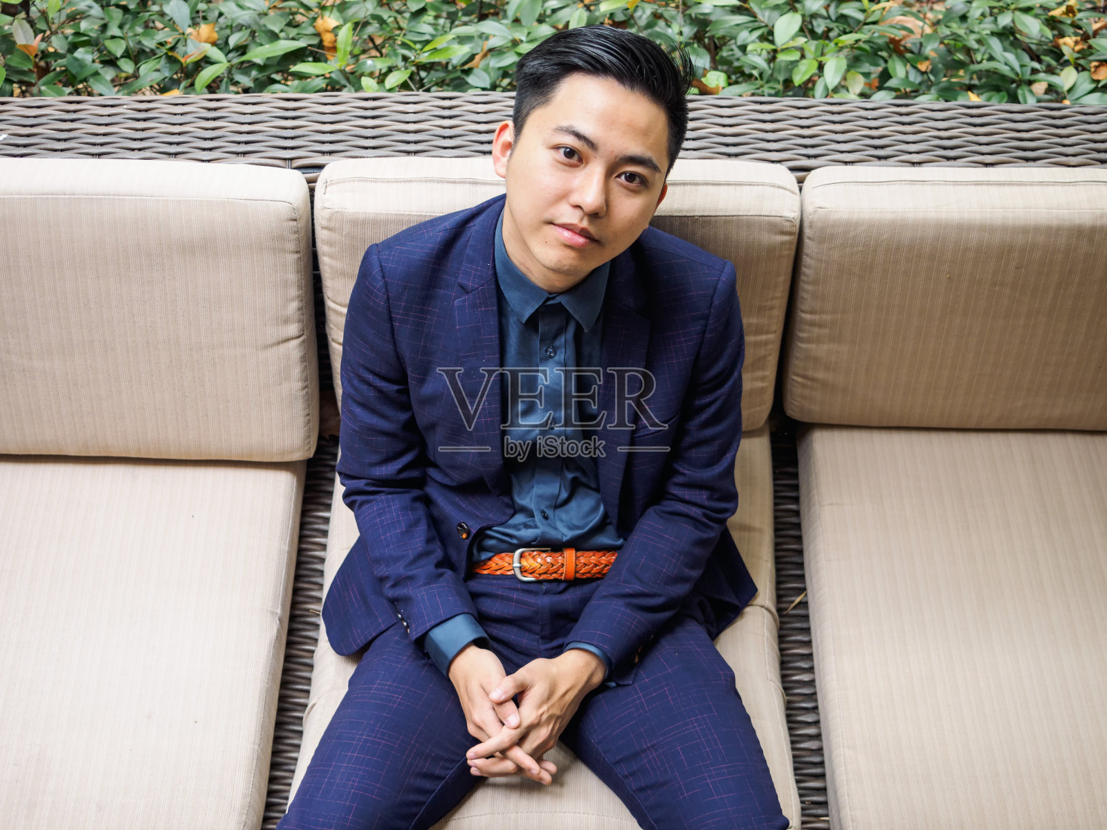 一个穿着蓝色西装的英俊的中国年轻人坐在外面向上看，俯视图。照片摄影图片