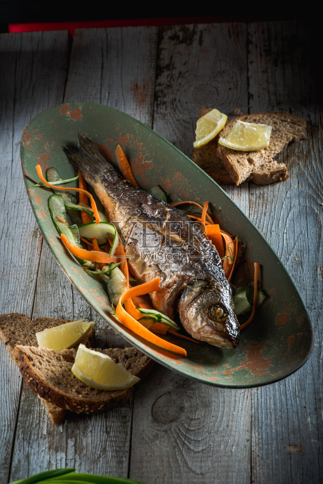 鱼和蔬菜放在旧盘子里烤照片摄影图片