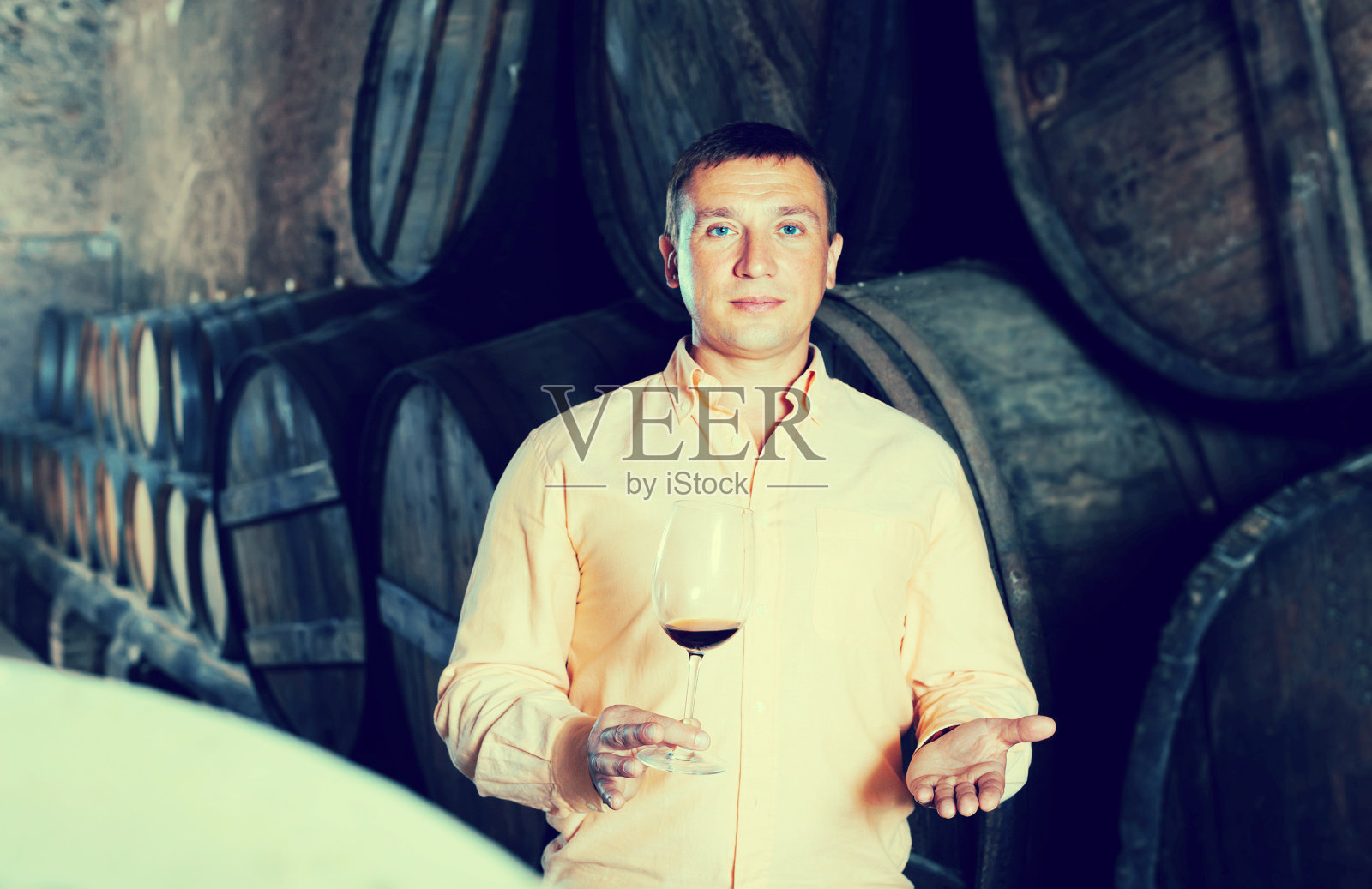 一名男子正在品尝木桶里的红酒照片摄影图片