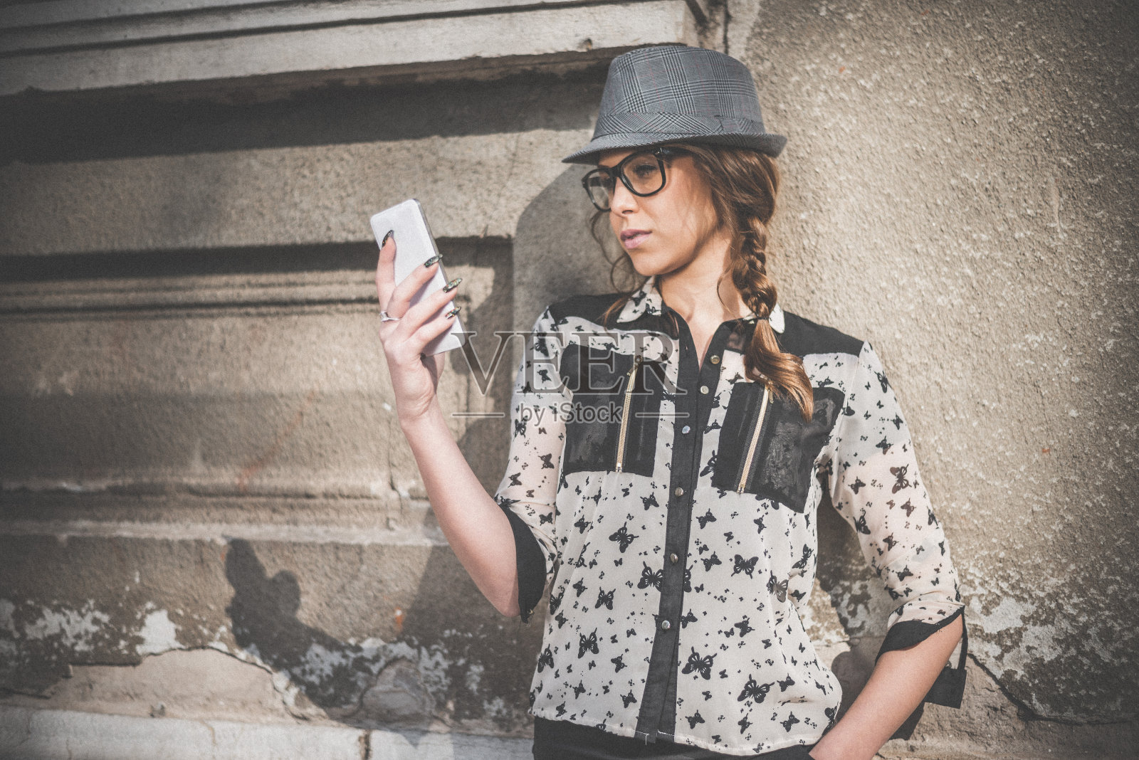 年轻的金发女人在城市背景下拿着智能手机照片摄影图片