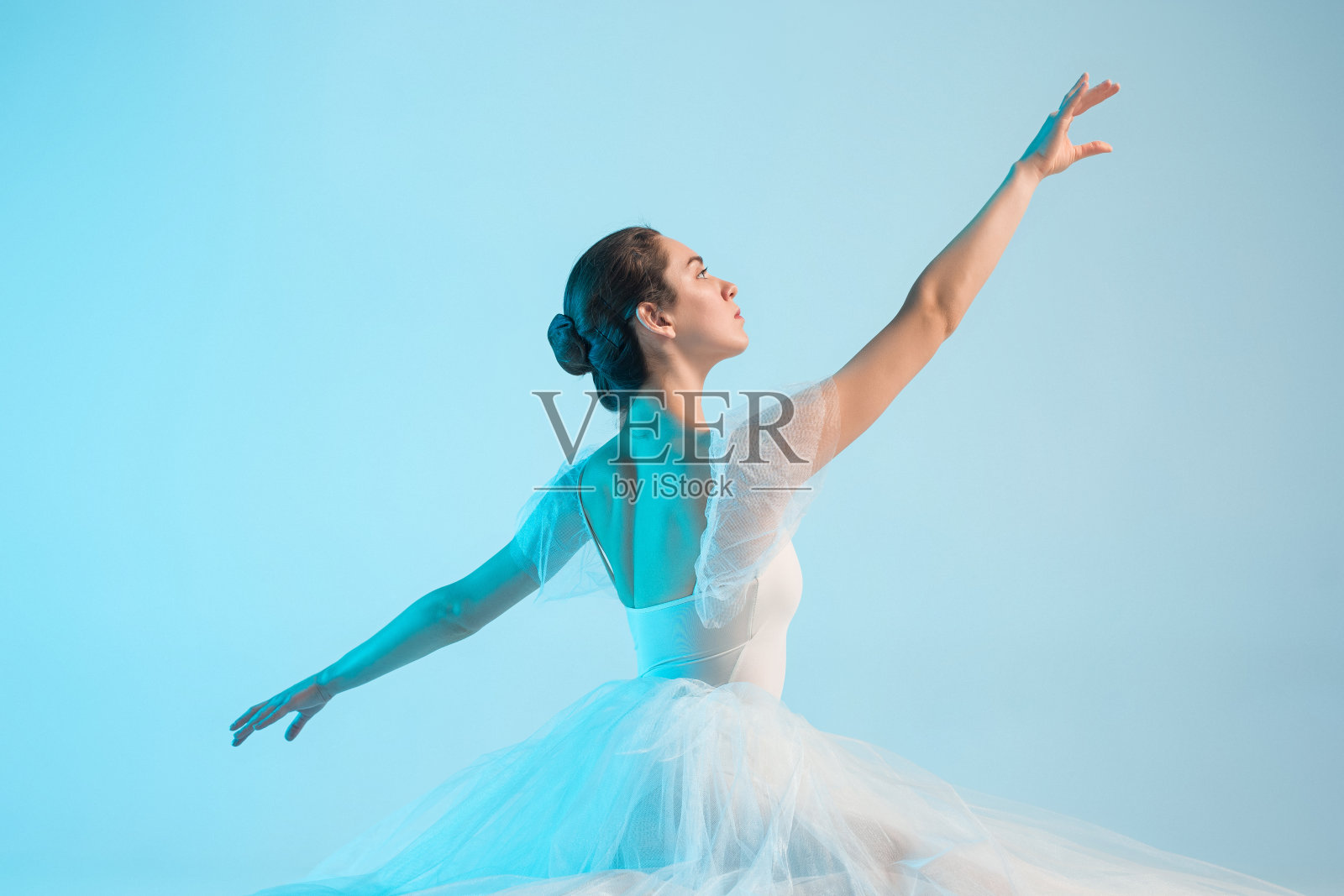 年轻美丽的芭蕾舞演员正在一个蓝色的演播室里跳舞照片摄影图片