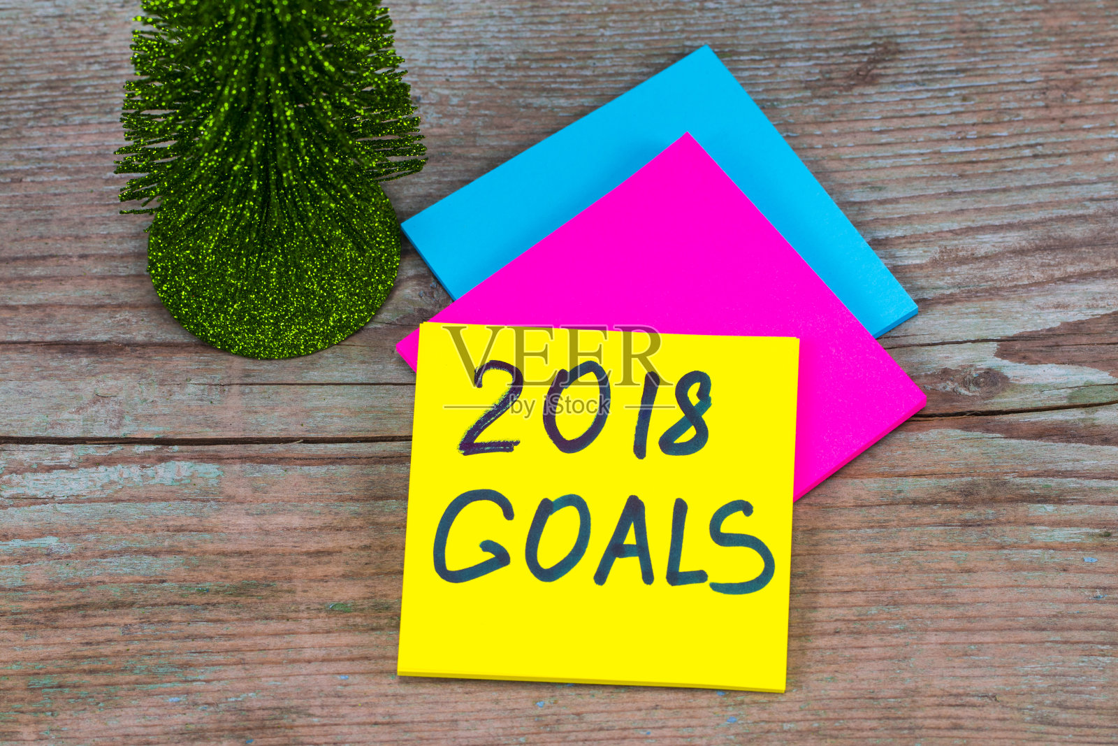 2018年目标——用黑色墨水在贴着圣诞树的便签上手写新年决心的概念照片摄影图片