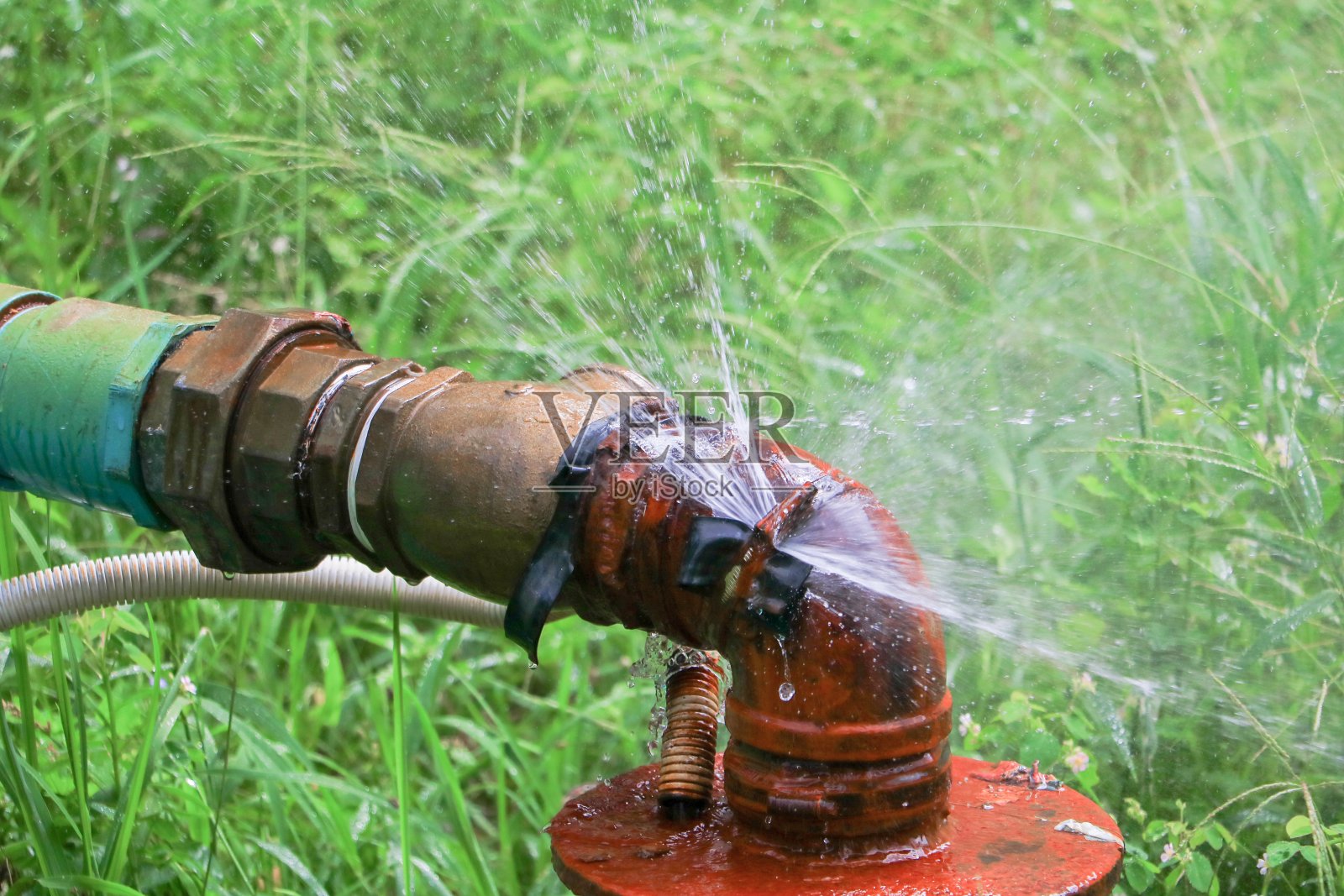 水管主管漏水，旧水管钢草地面生锈照片摄影图片