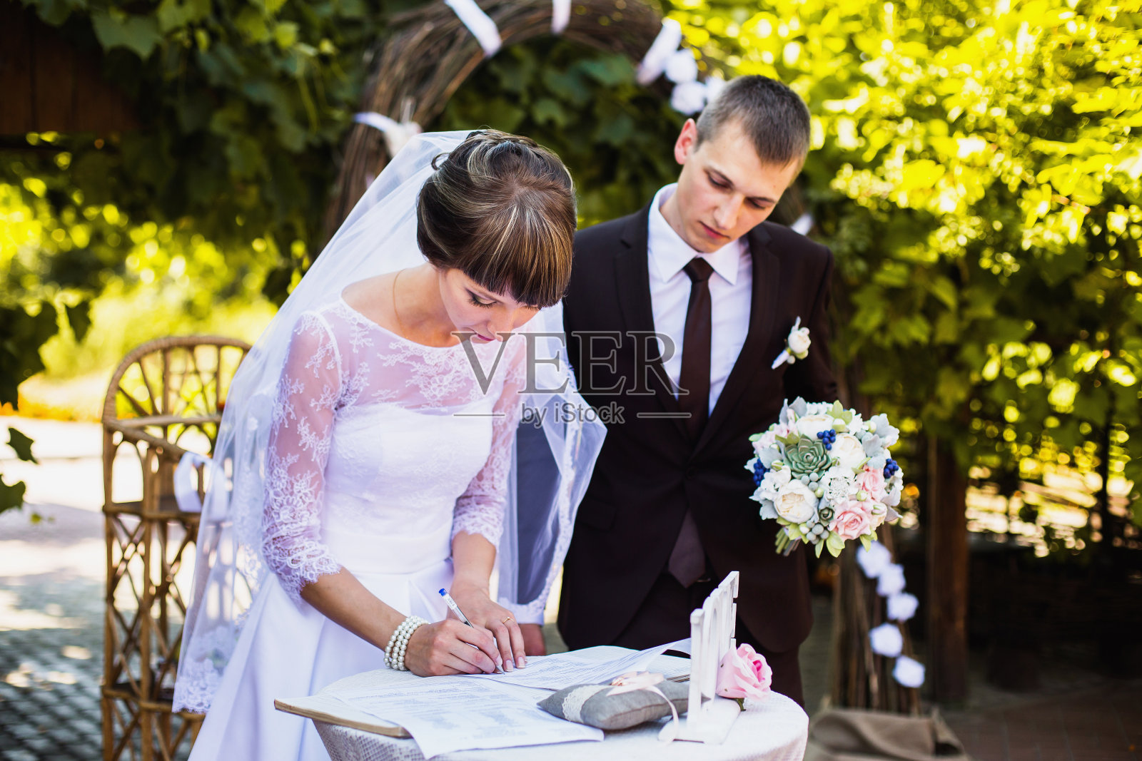 新郎和新娘身穿白色礼服，背景是拱门。婚礼仪式。幸福的家庭照片摄影图片