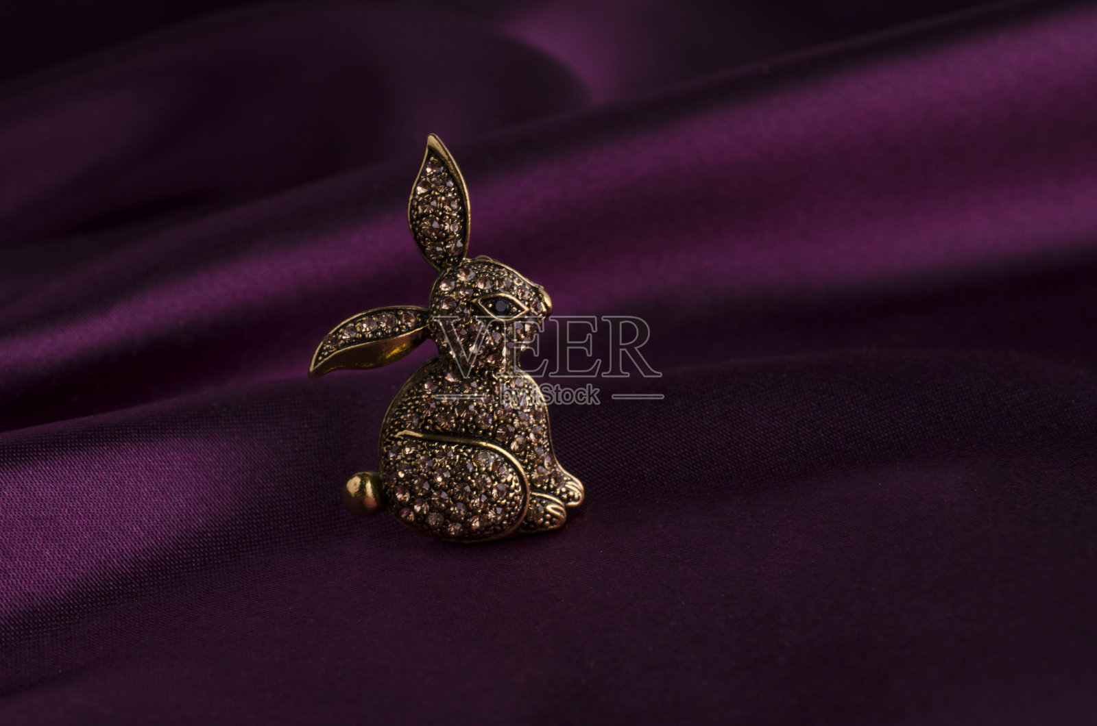金胸针兔子与钻石在丝绸上照片摄影图片