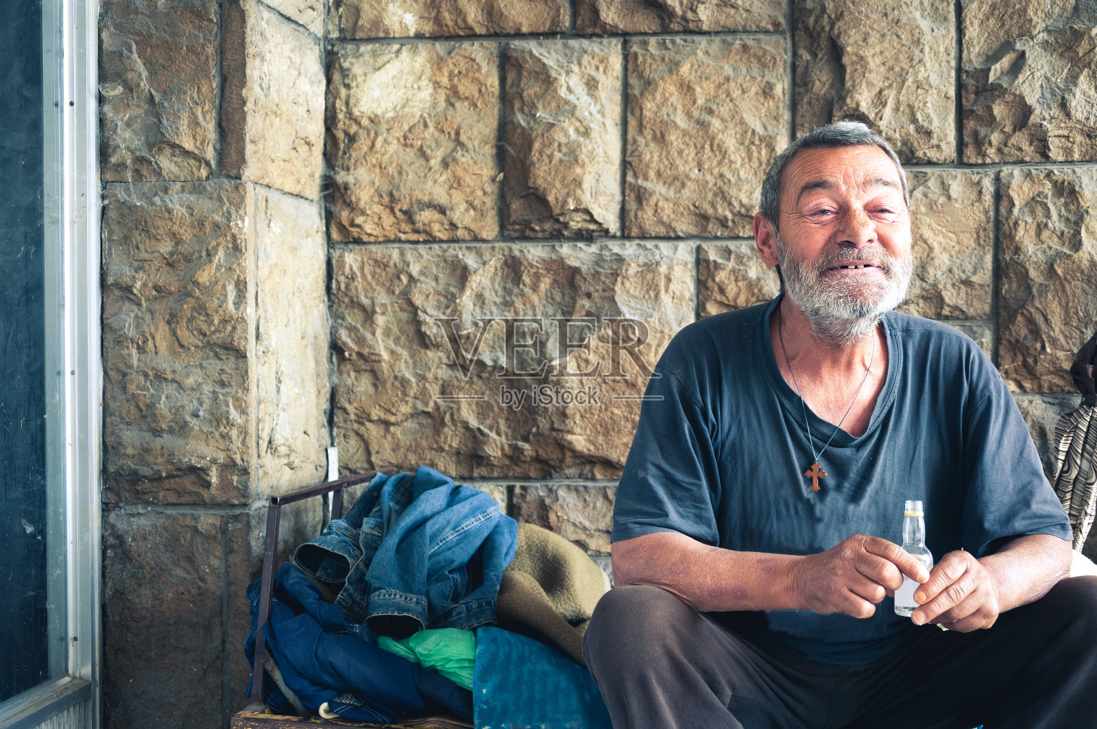 在城市街道建筑阴影中微笑的快乐无家可归男子照片摄影图片