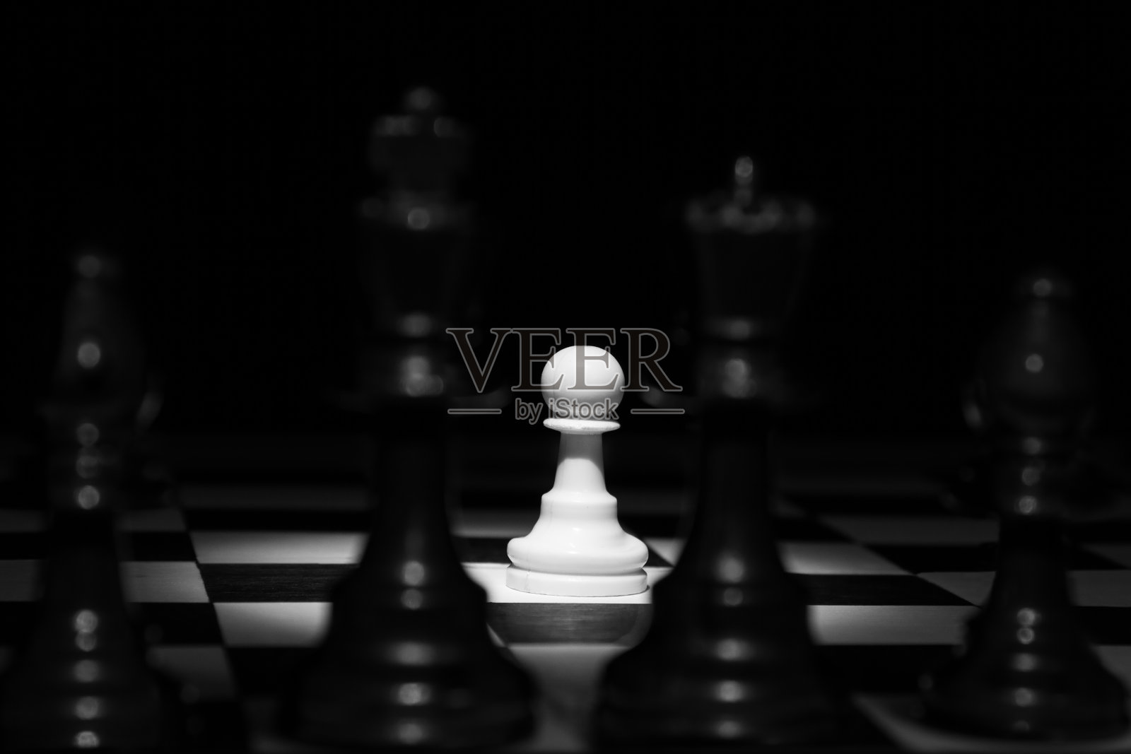 白卒独自站在聚光灯下，在棋盘上黑子之间艺术转换照片摄影图片