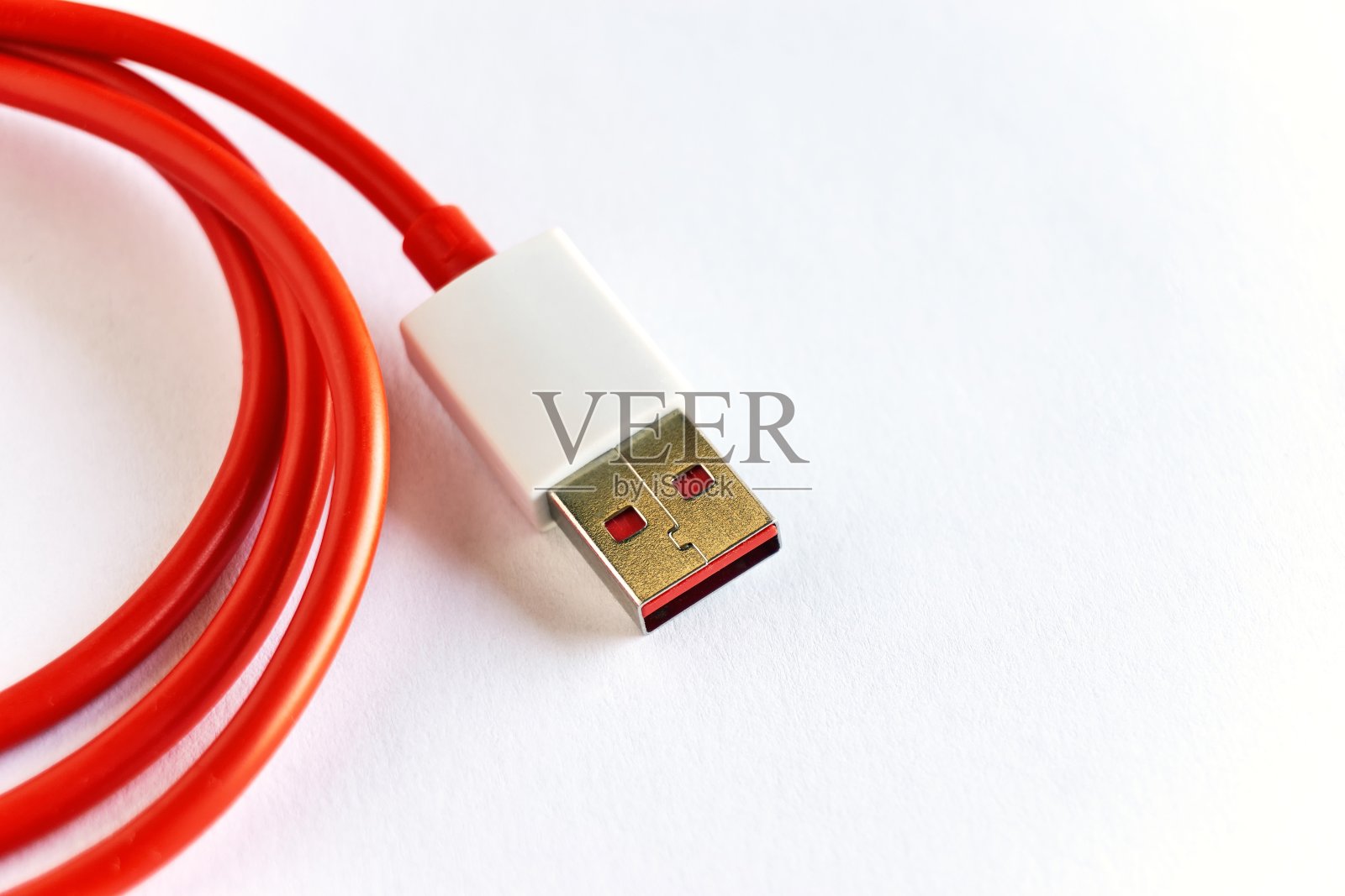 白色背景上的红色卷曲USB电缆的特写照片摄影图片