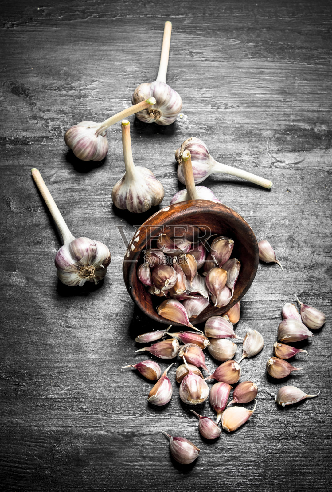 新鲜的蒜片放在一个木碗里。照片摄影图片