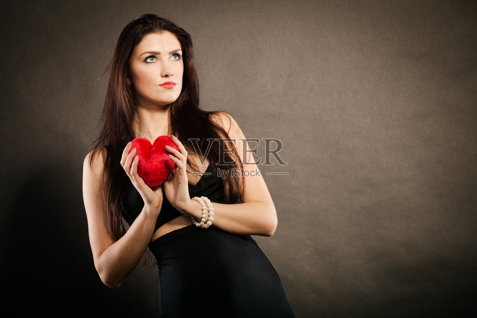 美丽的女人拿着黑衣上的红心照片摄影图片