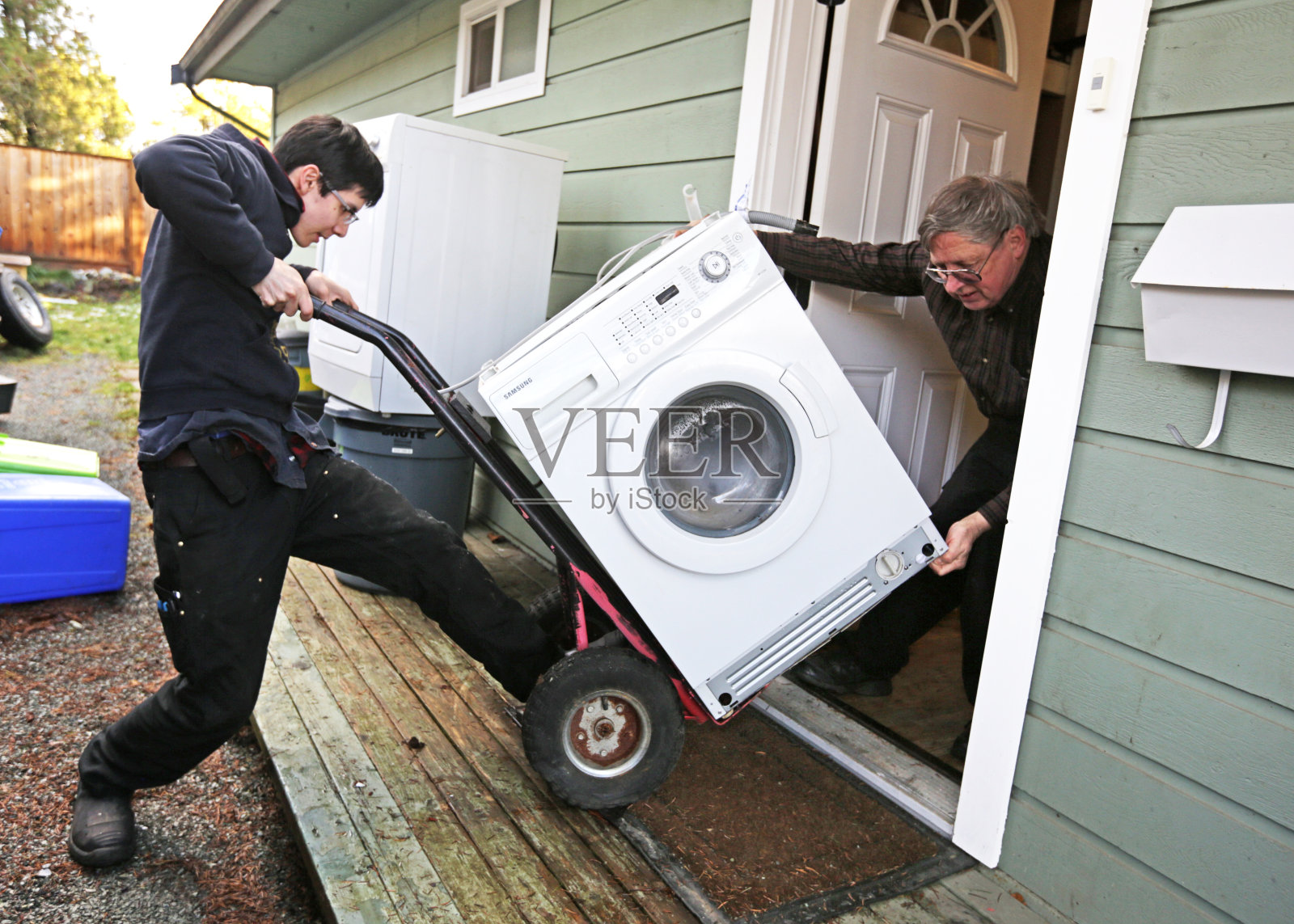 加拿大父子用团队合作来移动旧洗衣机照片摄影图片