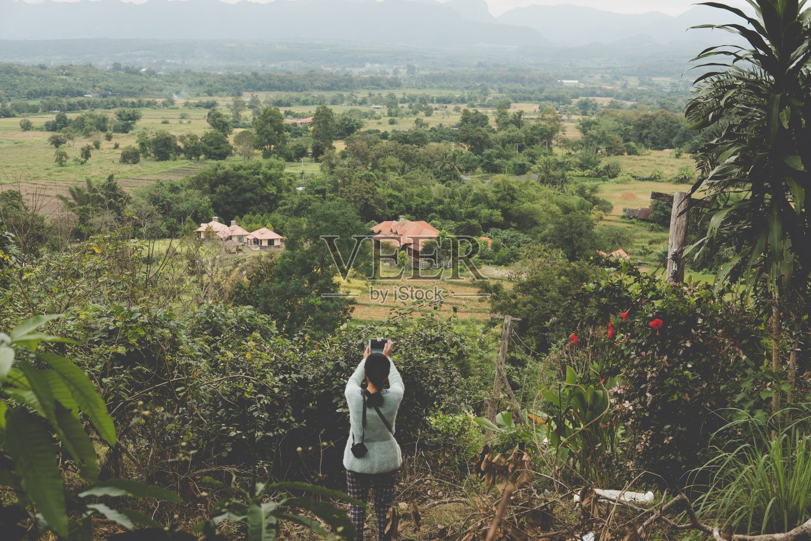 一名泰国女子用智能手机拍摄乡村风光。早晨的森林和山。照片摄影图片