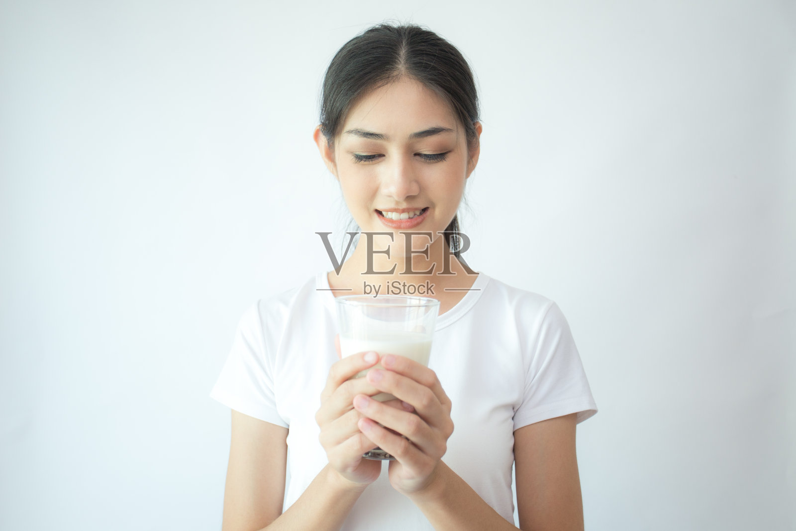 年轻的亚洲妇女抱着牛奶与微笑在白色的背景。照片摄影图片