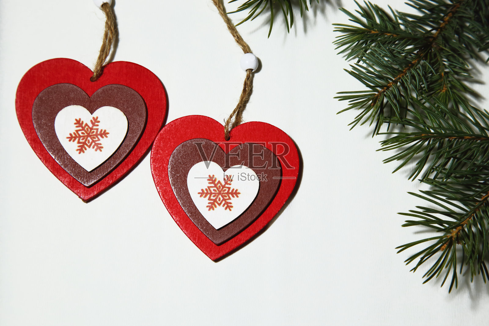 圣诞节，新年，圣瓦伦丁节，爱人。在白色的背景上有两颗彩色的心，上面有雪花和一根云杉。照片摄影图片