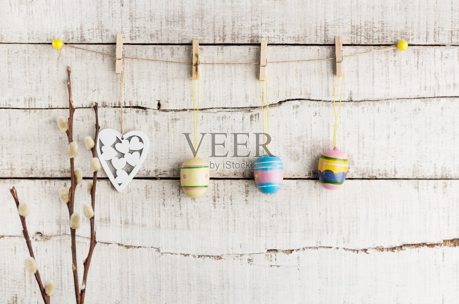 质朴的复活节背景:晒衣夹上挂着绘有复古彩蛋和白色心形图案的旧木墙。节日的概念照片摄影图片