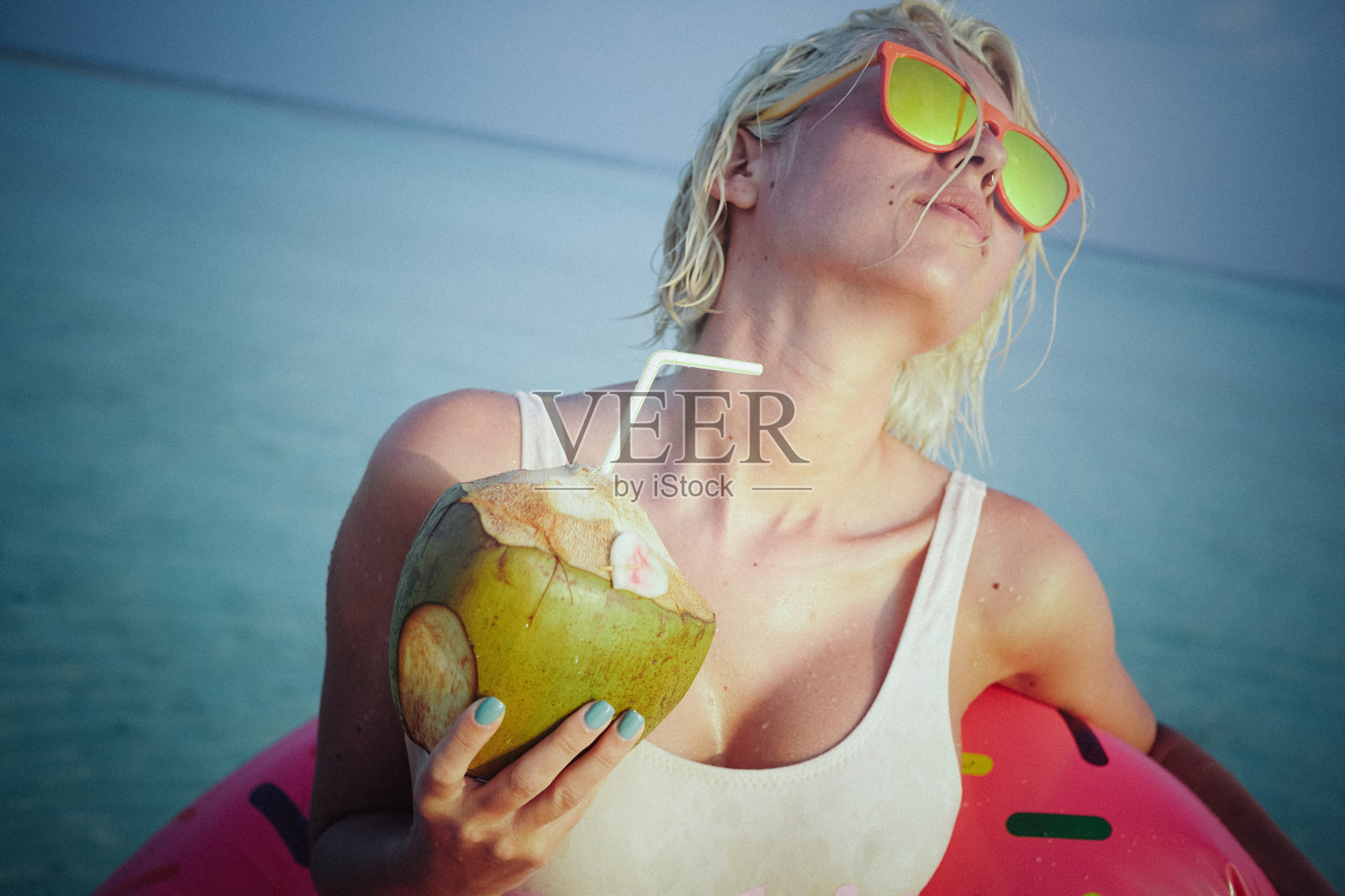 女人放松与椰子水旁边的海洋，马尔代夫照片摄影图片