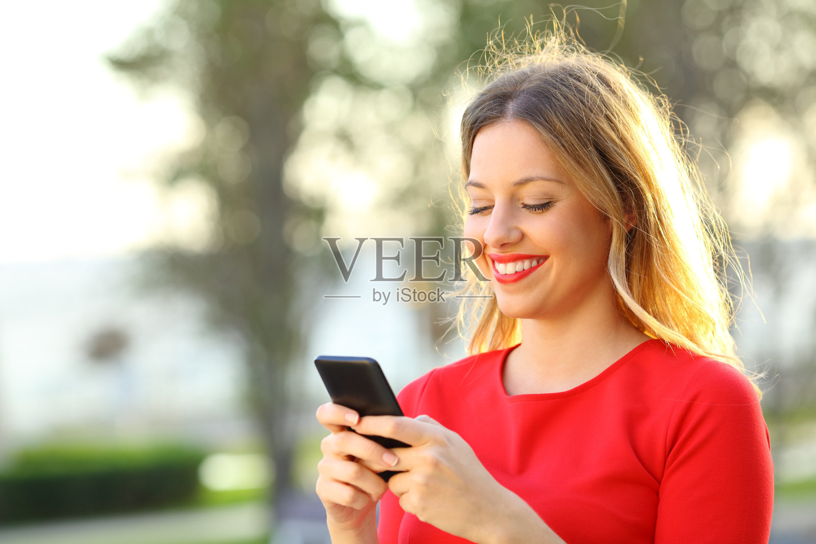 穿红衣服的女孩在外面用智能手机发短信照片摄影图片