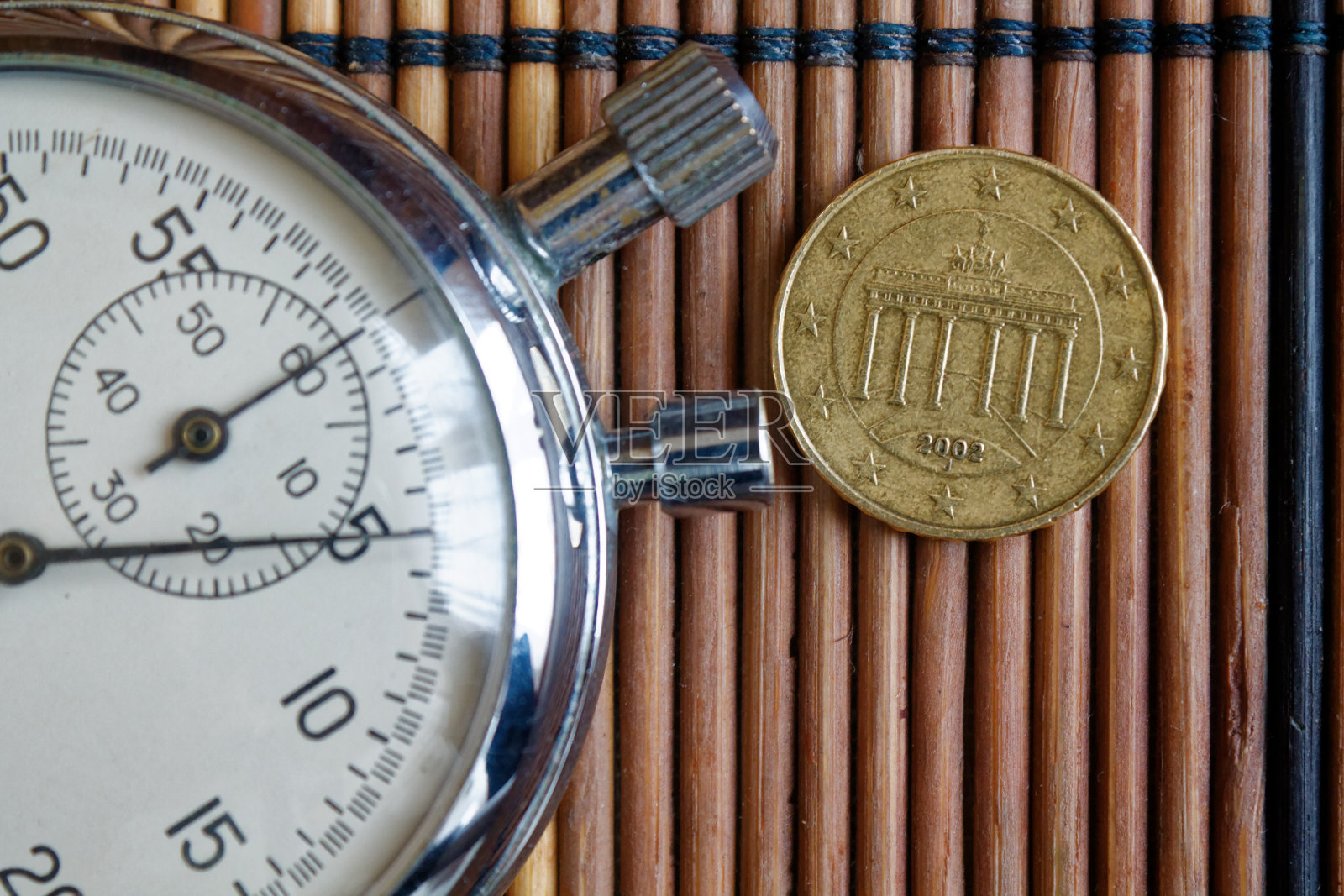 面值为10欧分的欧元硬币，码表在木制的桌子背面照片摄影图片