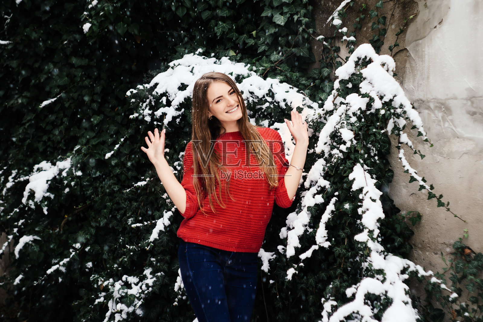 美丽的年轻女孩在冬天在公园里做模特。穿着一件红毛衣。照片摄影图片