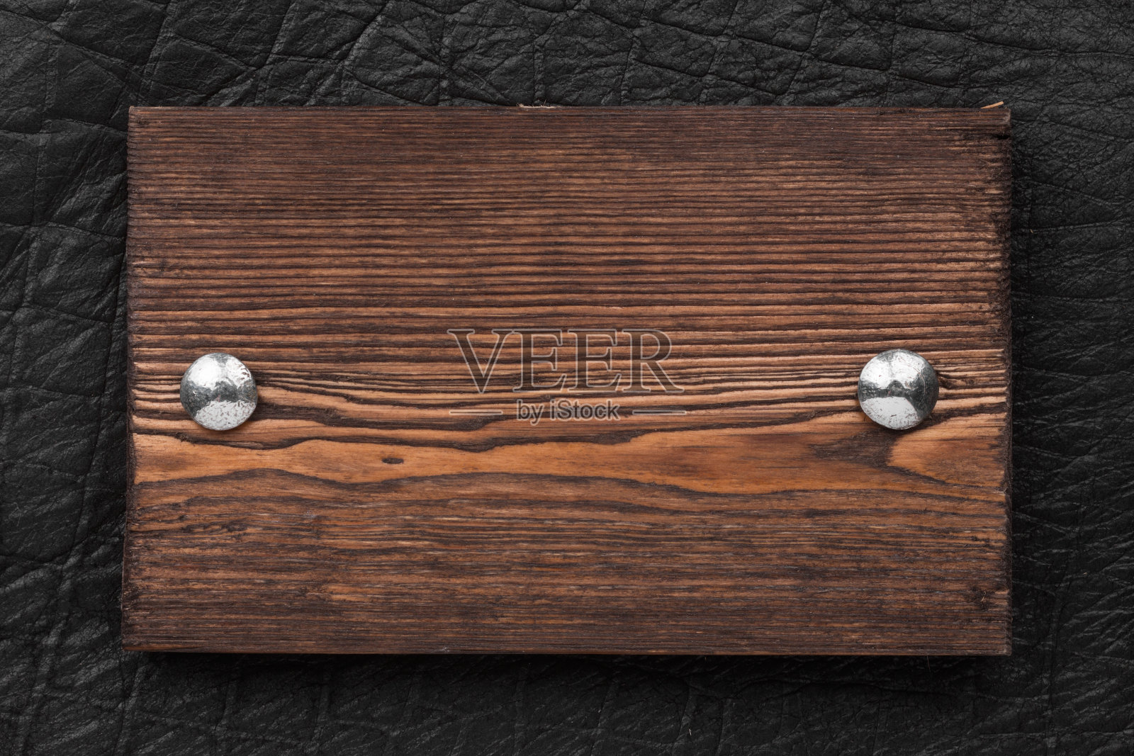 框架、边框由木头制成，用铁铆钉固定在黑色皮革上，孤立在白色背景上。照片摄影图片