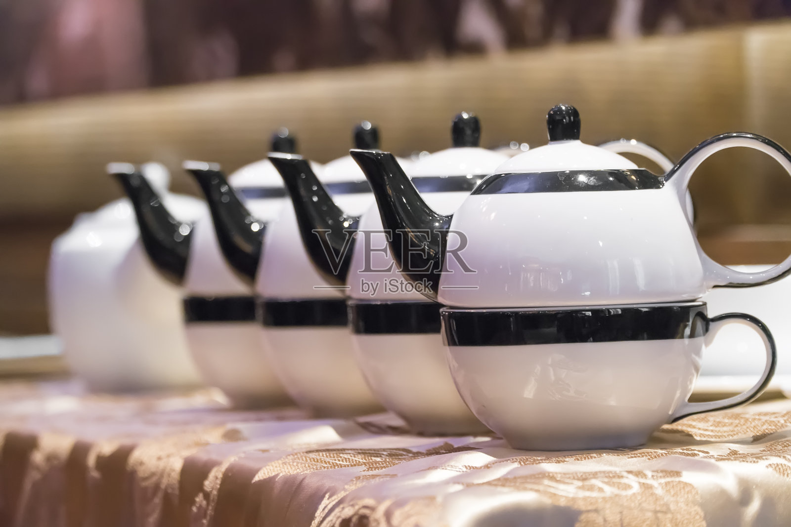 把茶倒进木头表面的杯子里的茶壶照片摄影图片