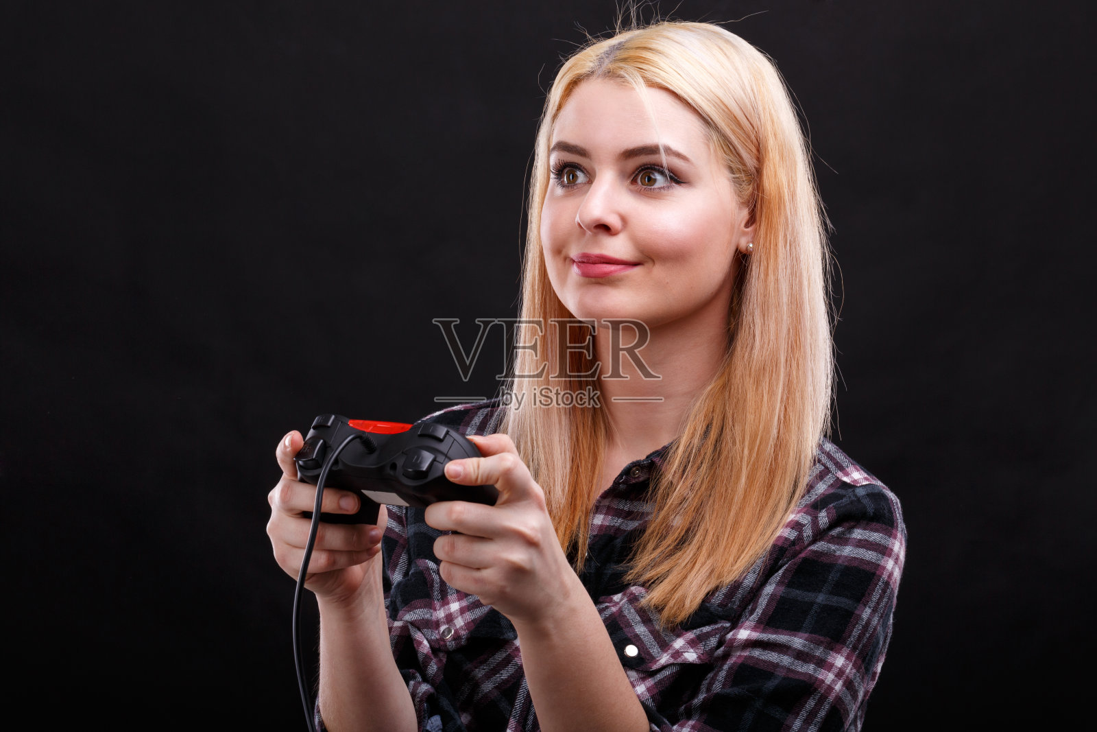 情绪化的女孩，迷人地玩着游戏操纵杆。在黑色的背景上。照片摄影图片